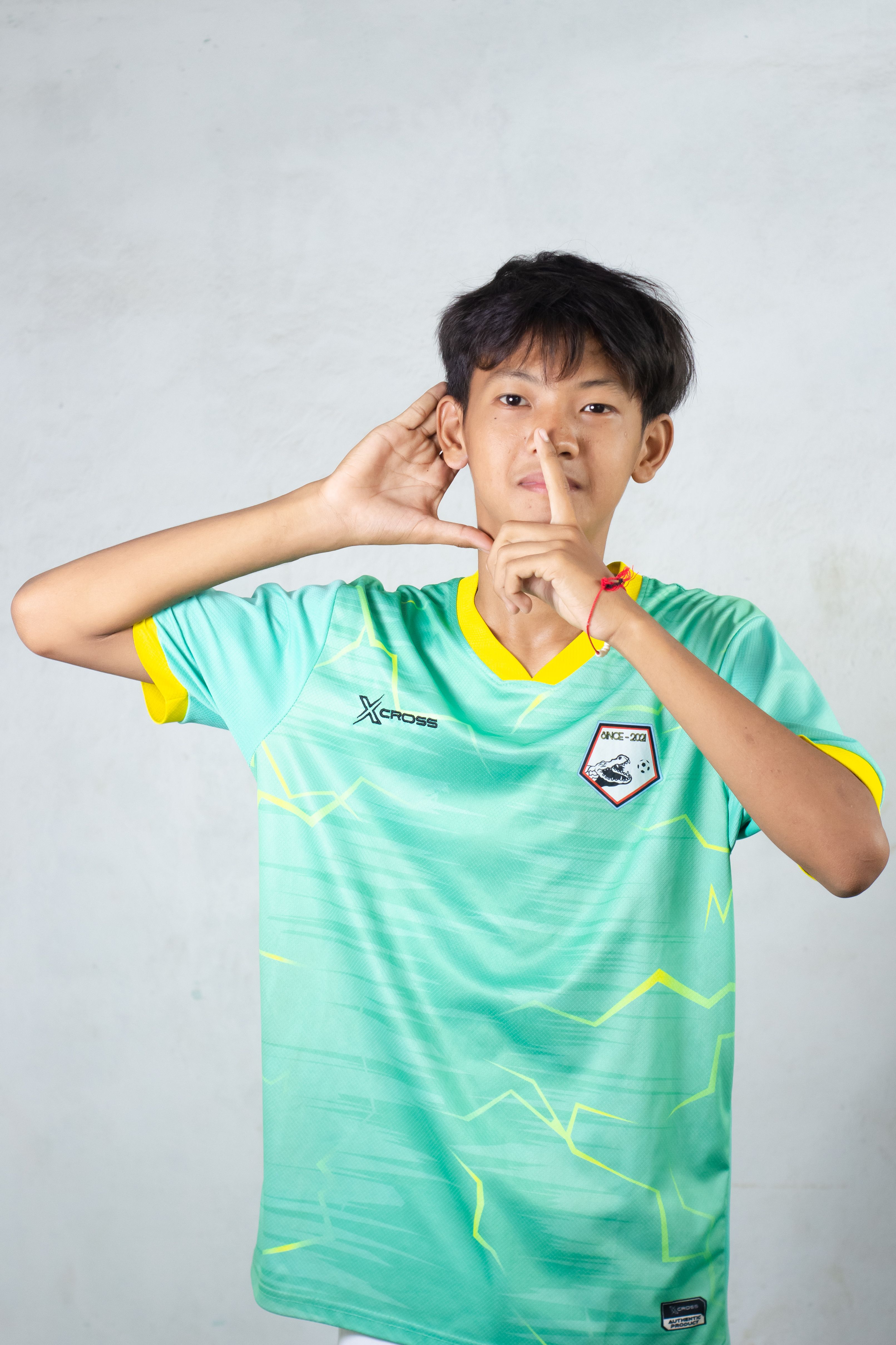 Portrait of a teenage boy making a silence gesture, wearing a sports jersey in Myanmar.