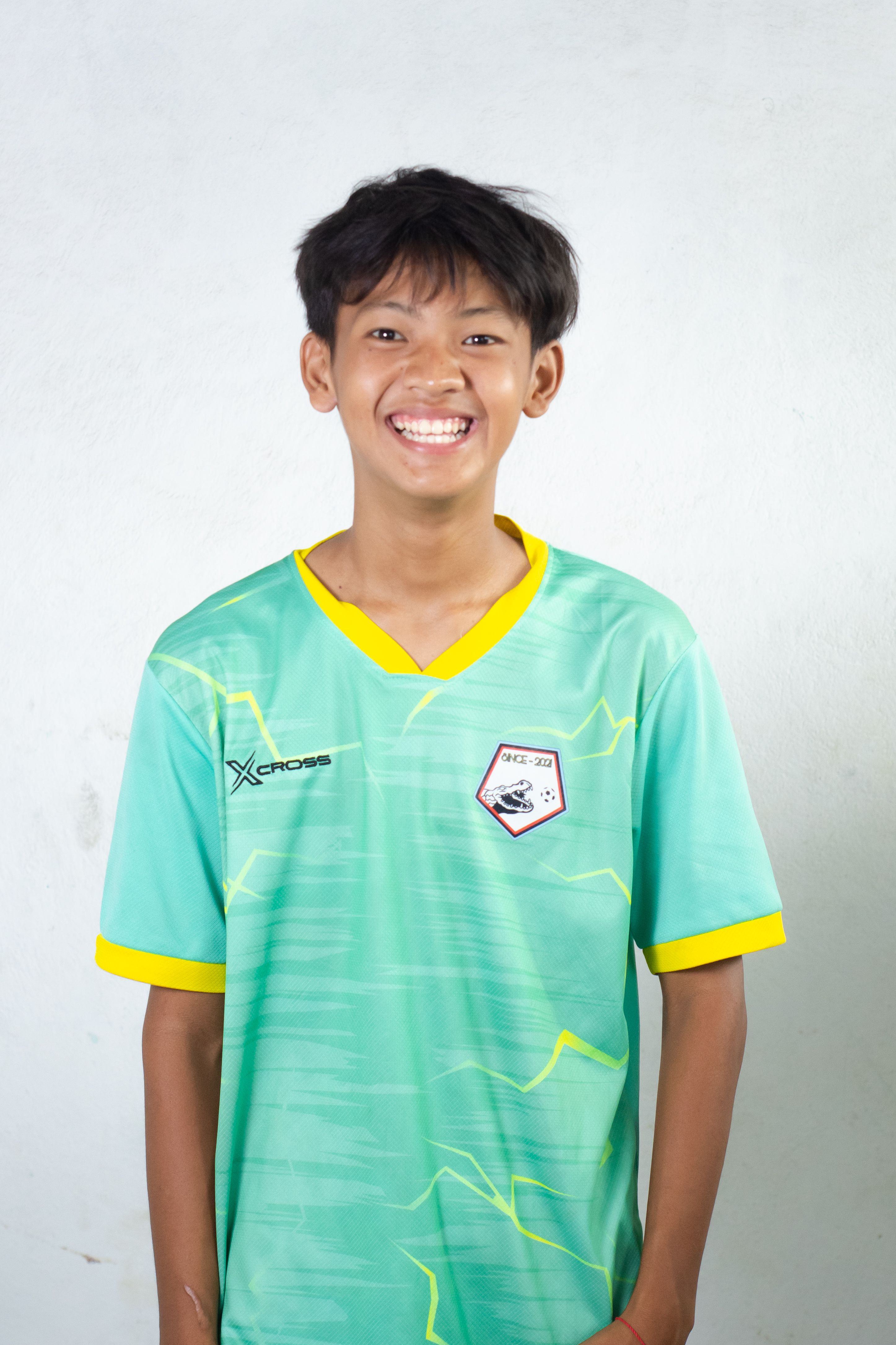 Bright portrait of a smiling teenager wearing a sports jersey against a plain background.