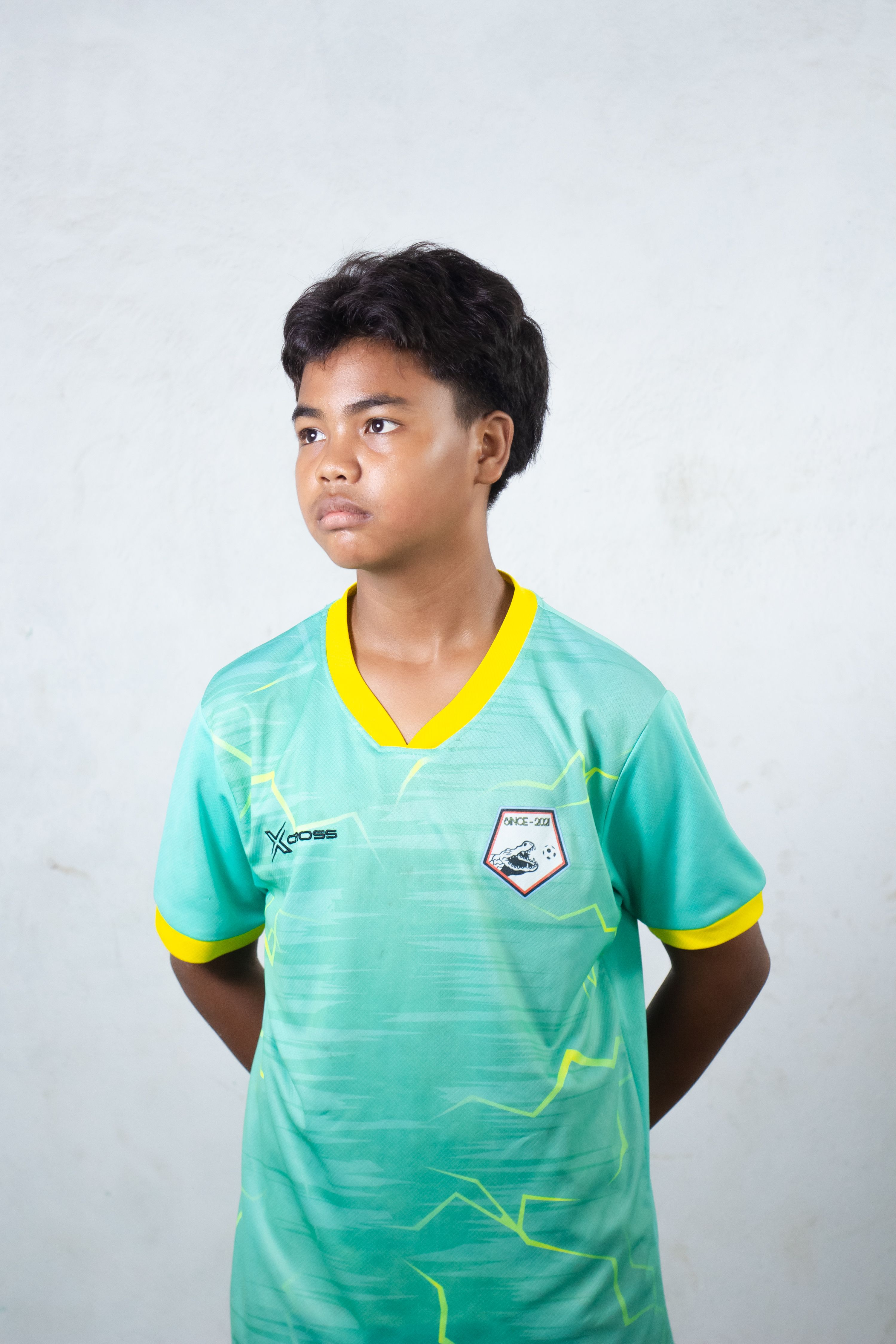 Young soccer player in uniform posing confidently against a plain background.