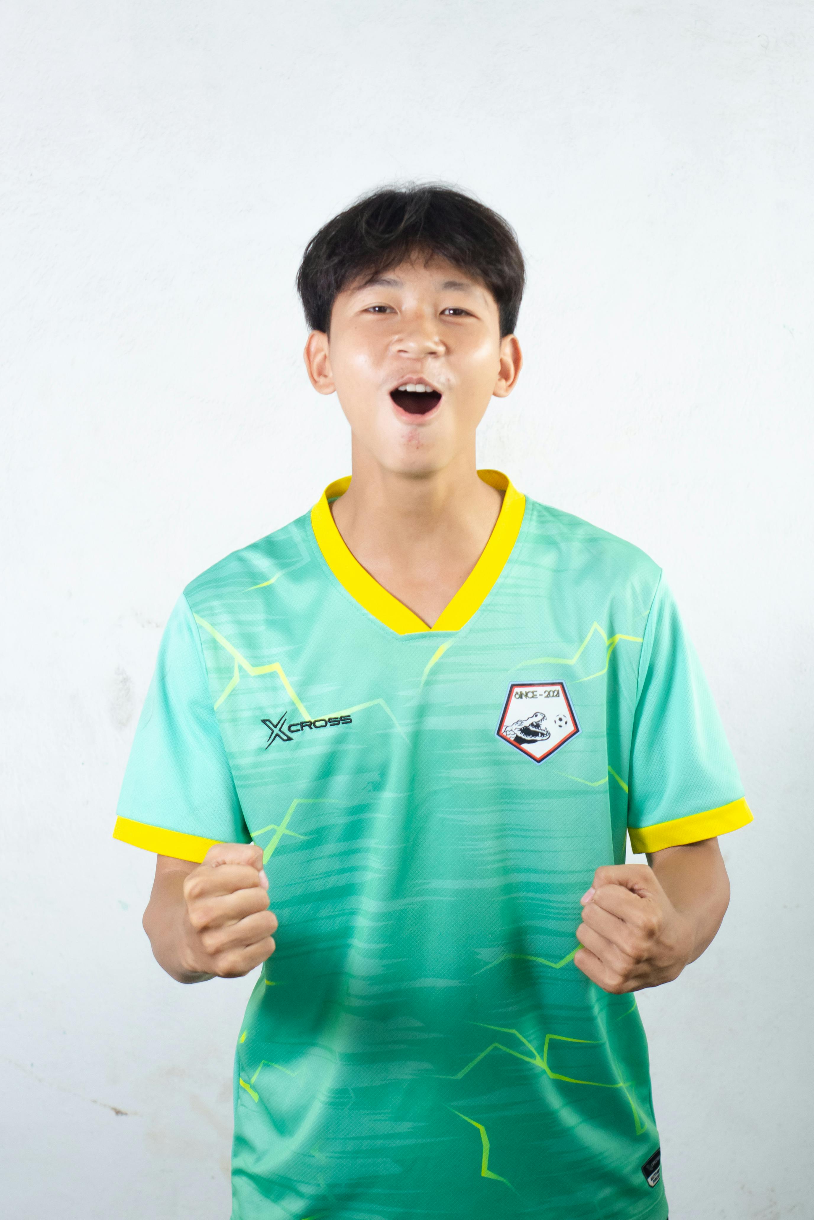 Young man celebrating victory, wearing a sports jersey with enthusiasm.