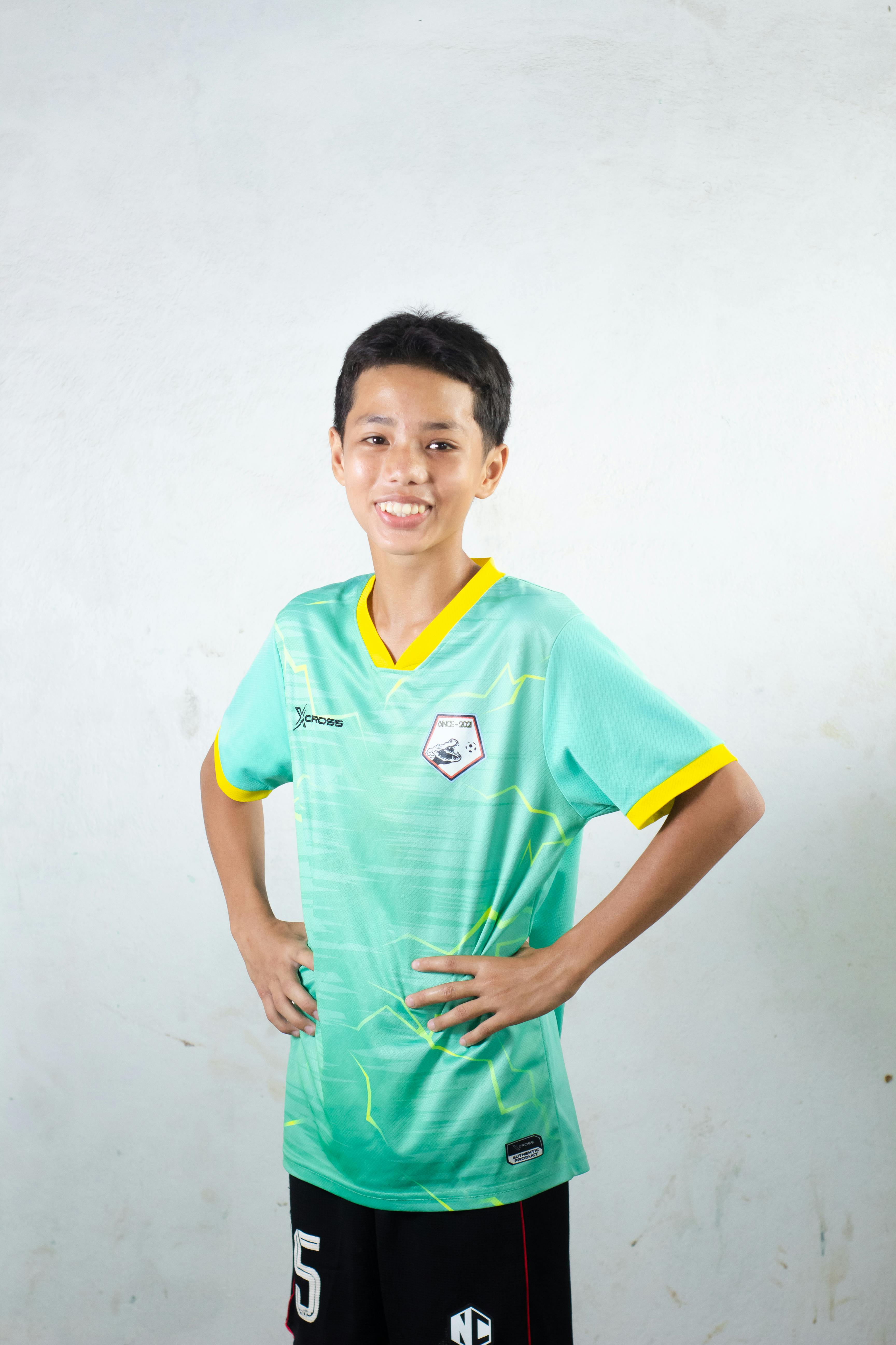 Smiling teenager in sportswear posing confidently against a white background.