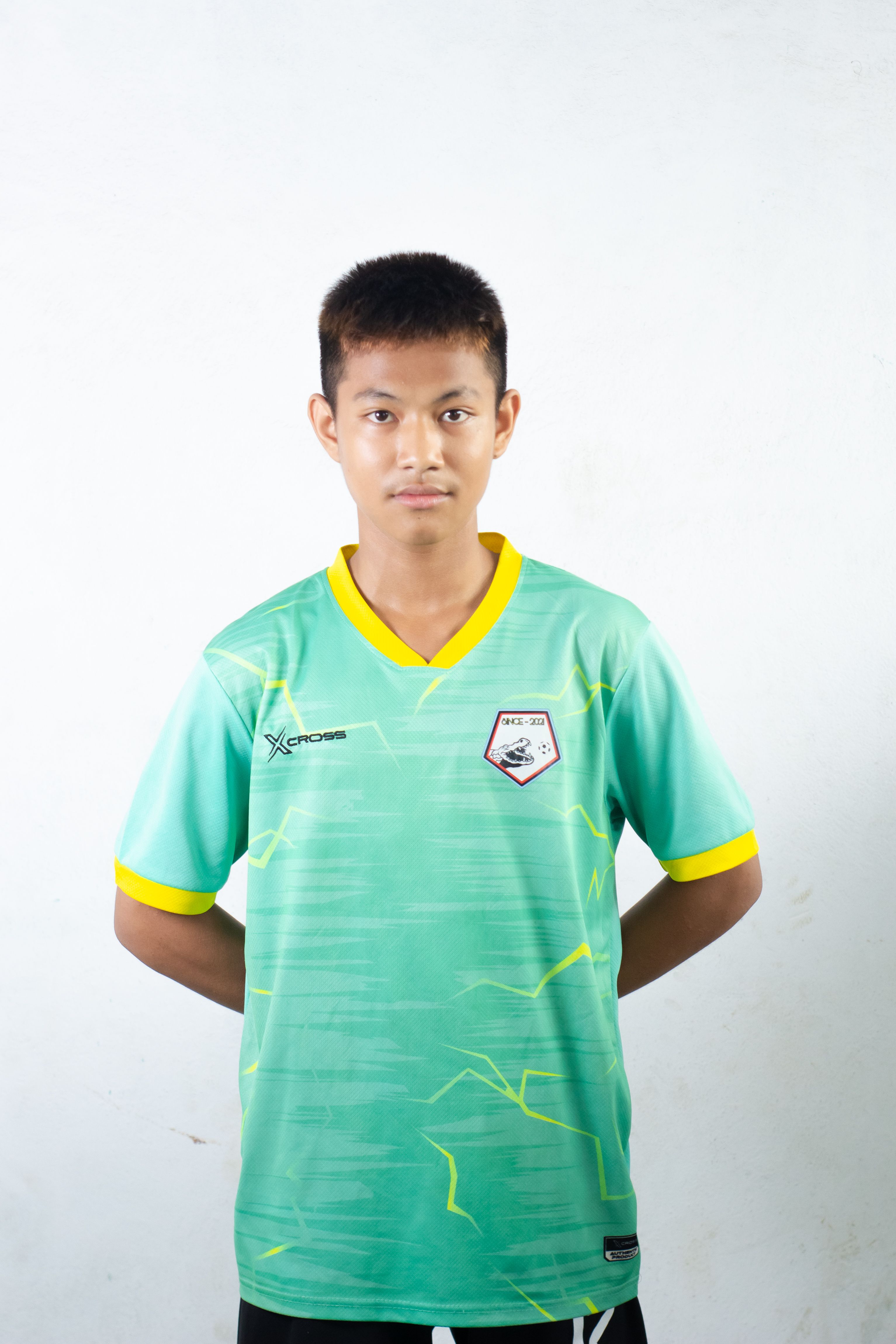 A teenager in a green sports jersey posing confidently against a plain background.