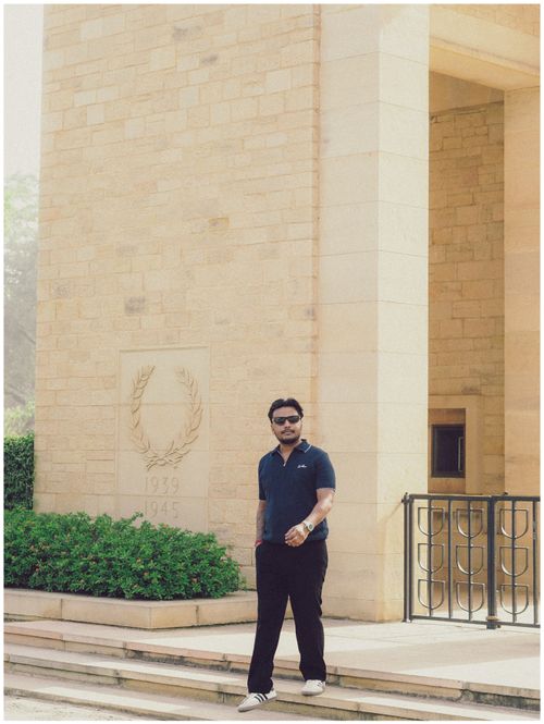 Free Man posing outside a stone monument with a wreath engraving. Casual and contemplative. Stock Photo
