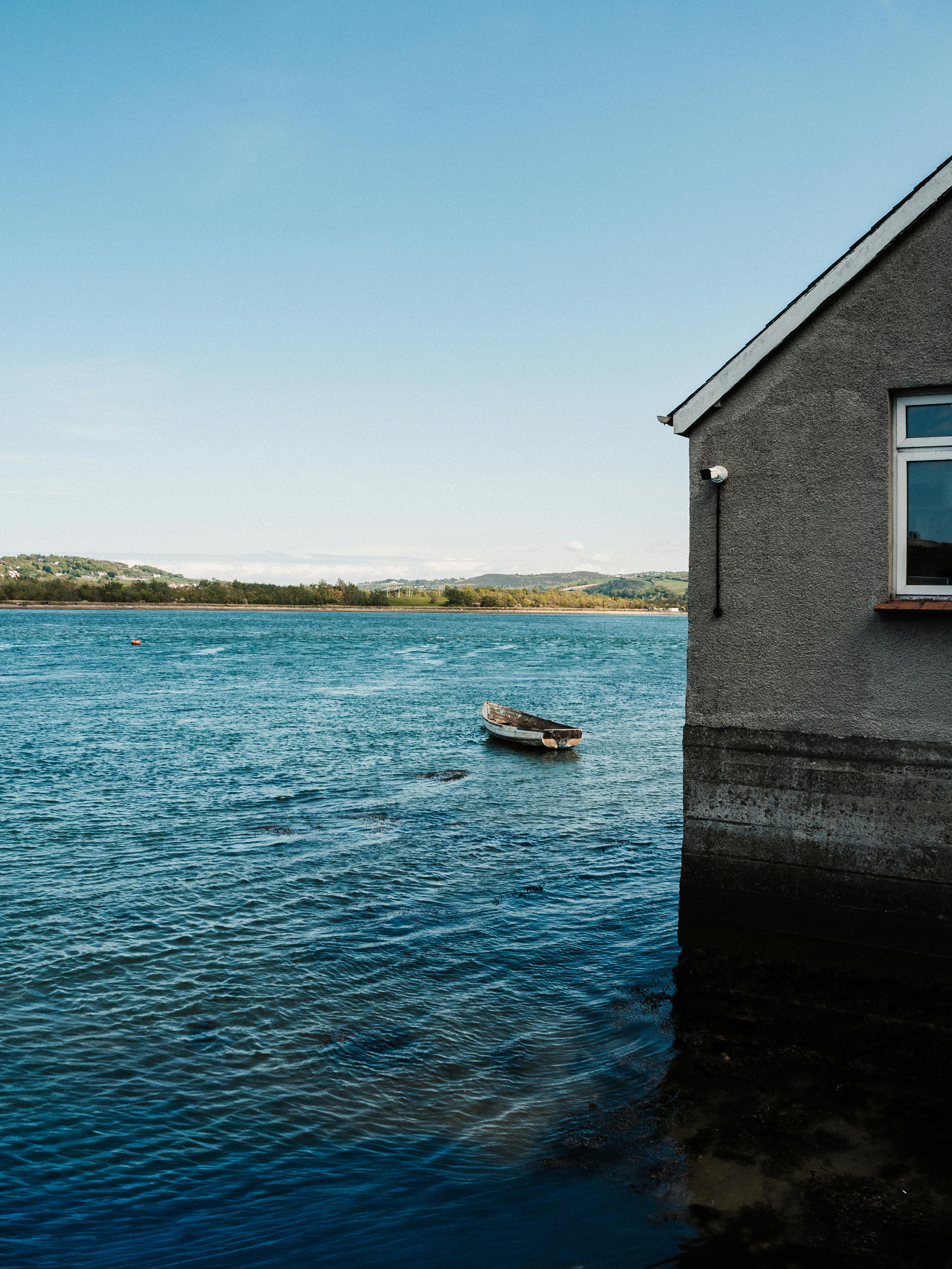 A serene view of a small boat near a building on the river in Conwy, Wales.