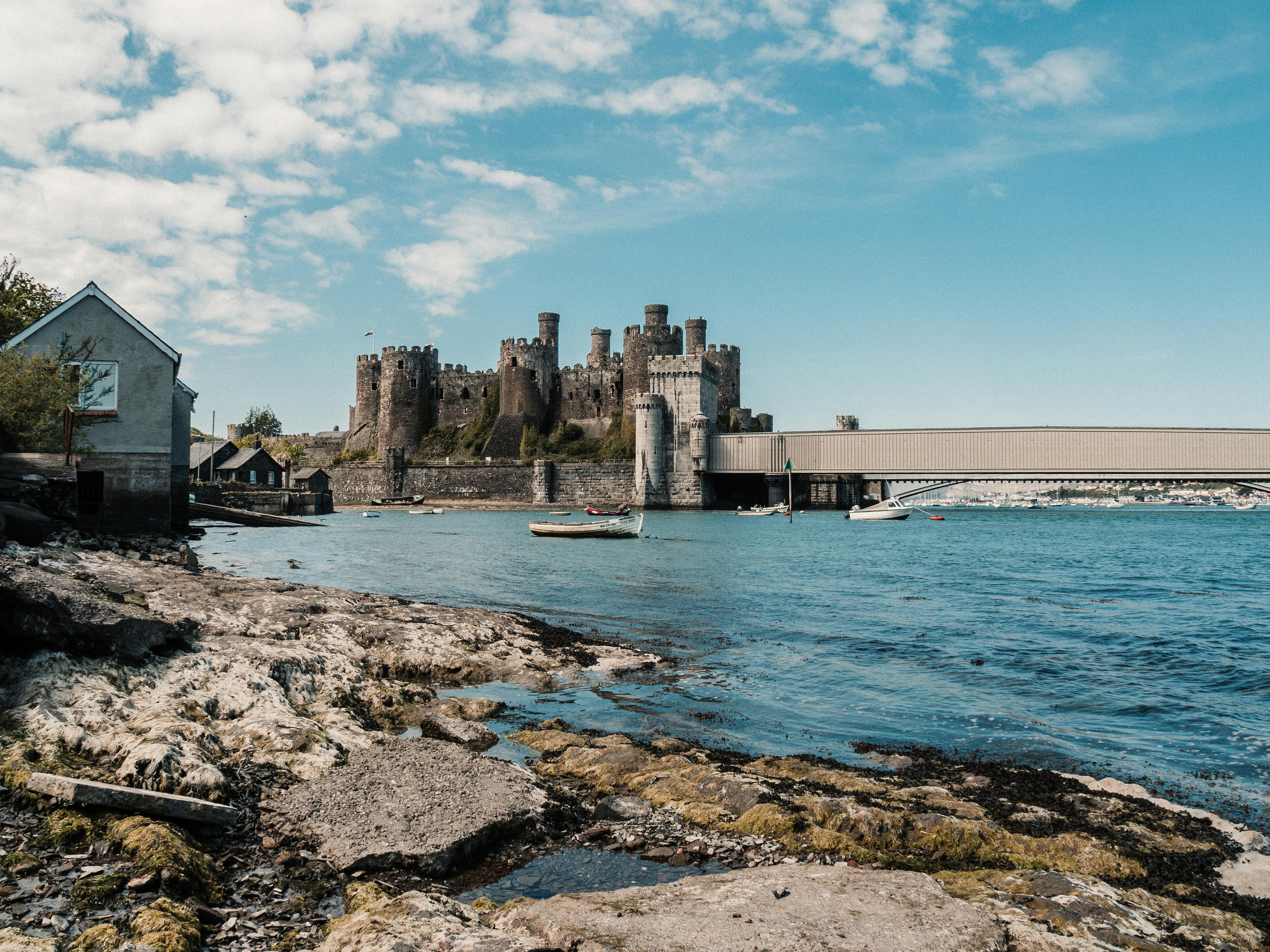 Idyllic view of Conwy Castle with blue sky and calm sea, showcasing Welsh heritage and landscapes.