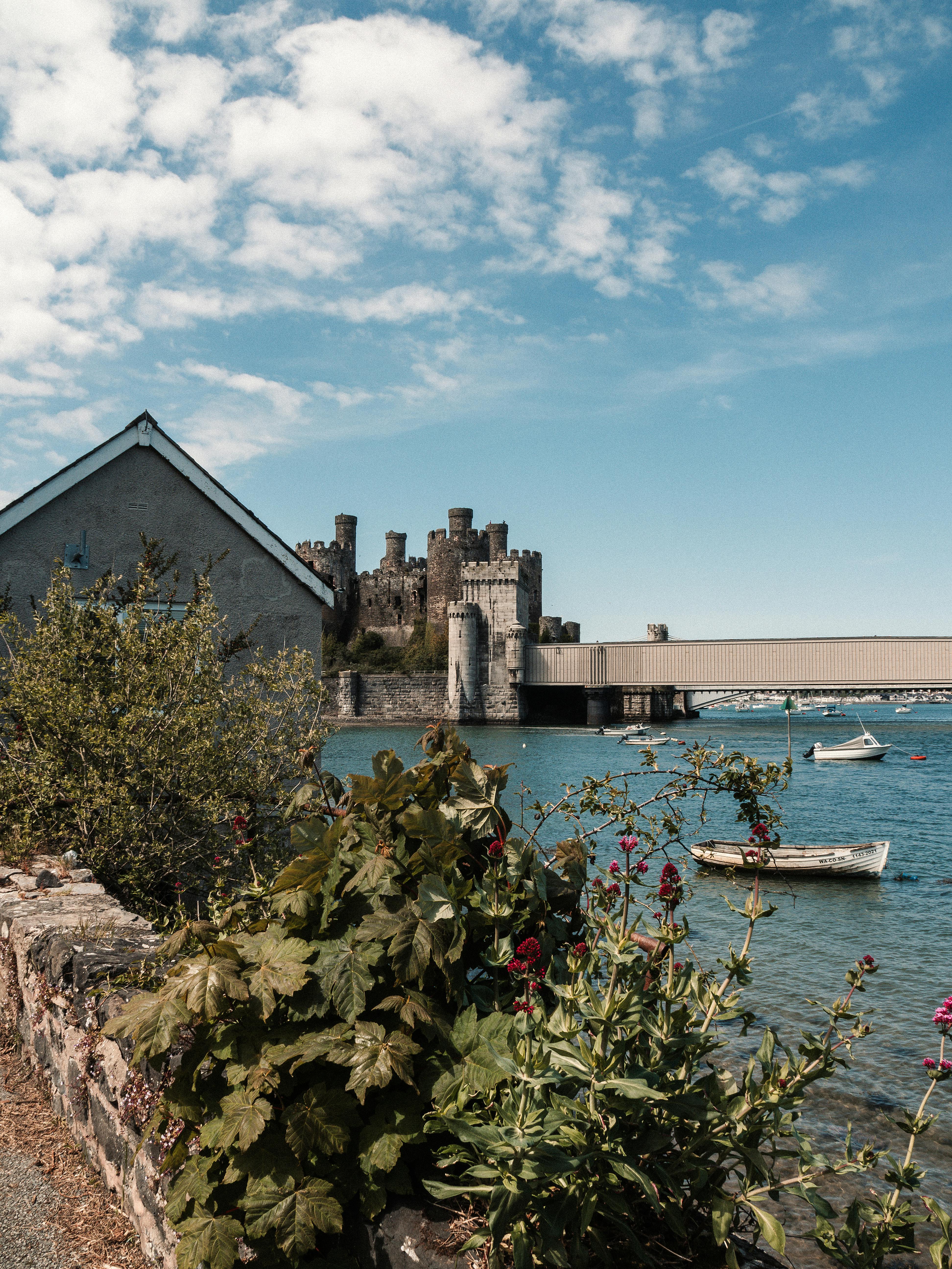 Picturesque view of Conwy Castle and river in Wales with boats and blue skies