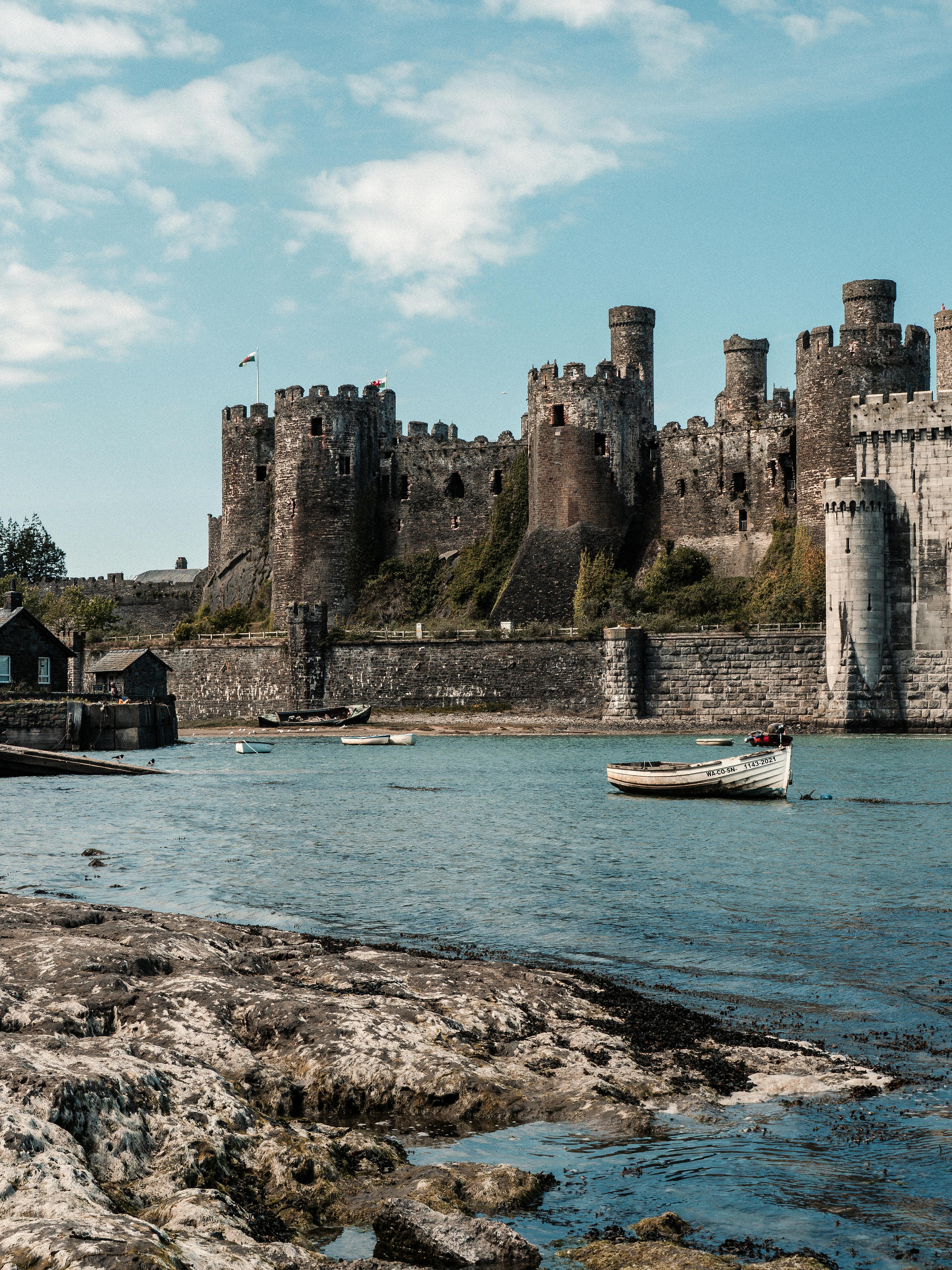 View of Conwy Castle with boats on the river, under a blue sky in Wales.