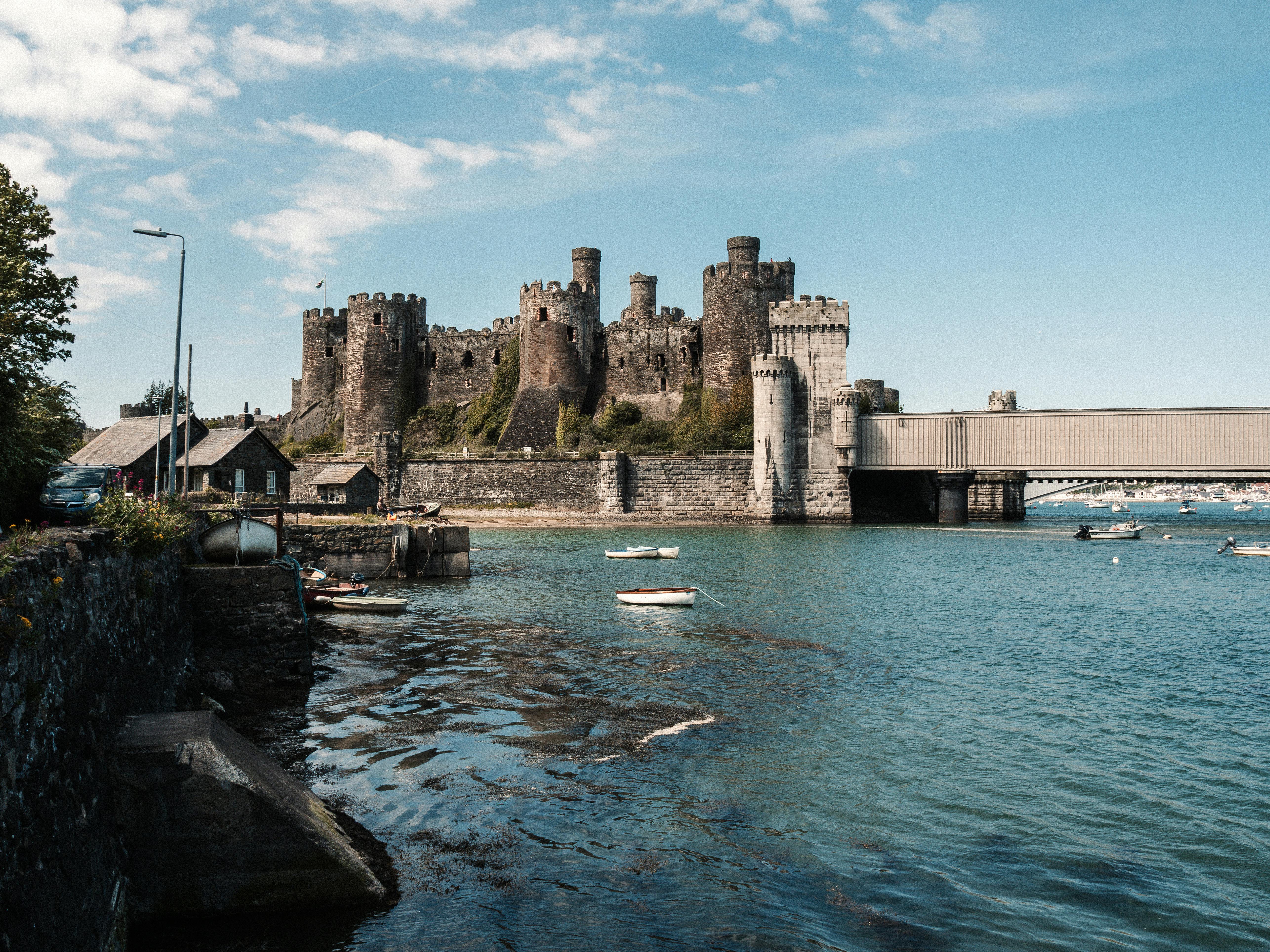 Historic Conwy Castle on a sunny day, stunningly reflected in a calm bay.
