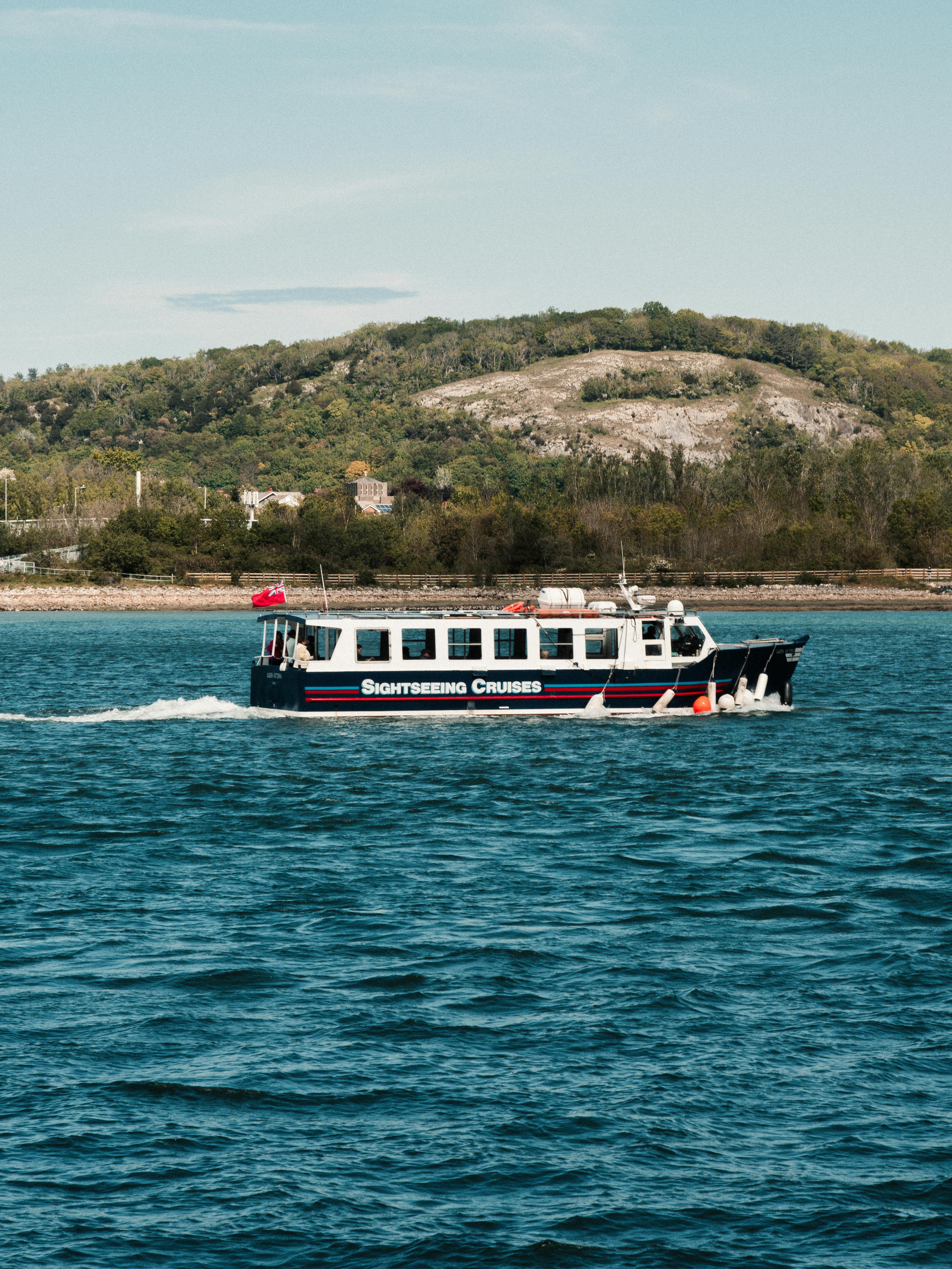 A sightseeing cruise boat travels across the scenic waters of Conwy, Wales.
