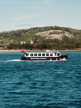 A sightseeing cruise boat travels across the scenic waters of Conwy, Wales.