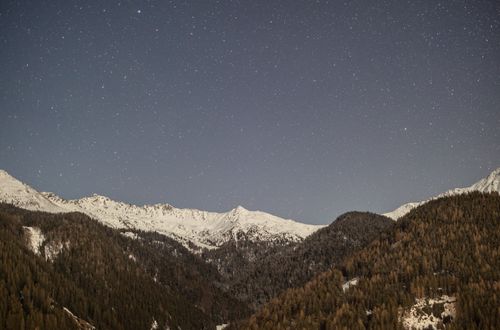 Free Breathtaking view of snow-capped mountains under a star-filled night sky in the Italian Alps. Stock Photo