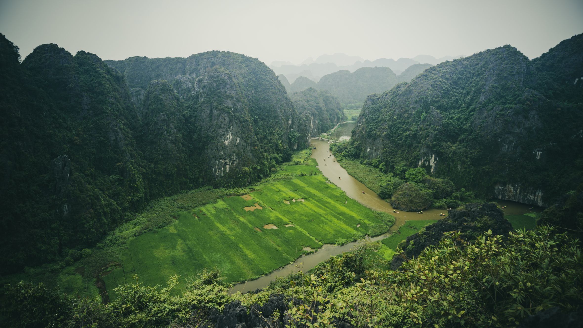 A breathtaking aerial view of lush green fields and winding rivers in Tam Coc, Ninh Bình, Vietnam.