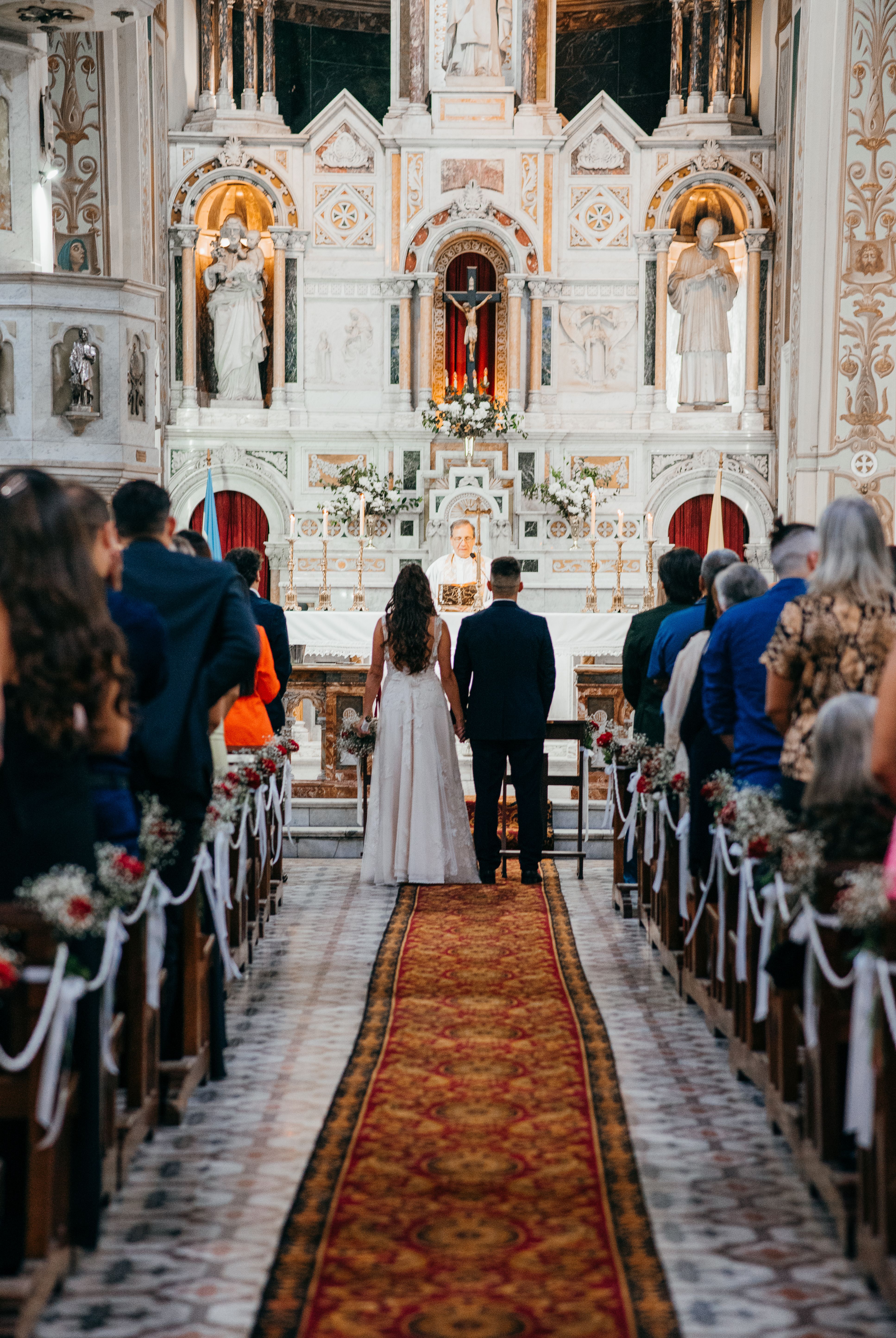 Bride and groom standing at altar in a beautiful church wedding ceremony, attended by guests.
