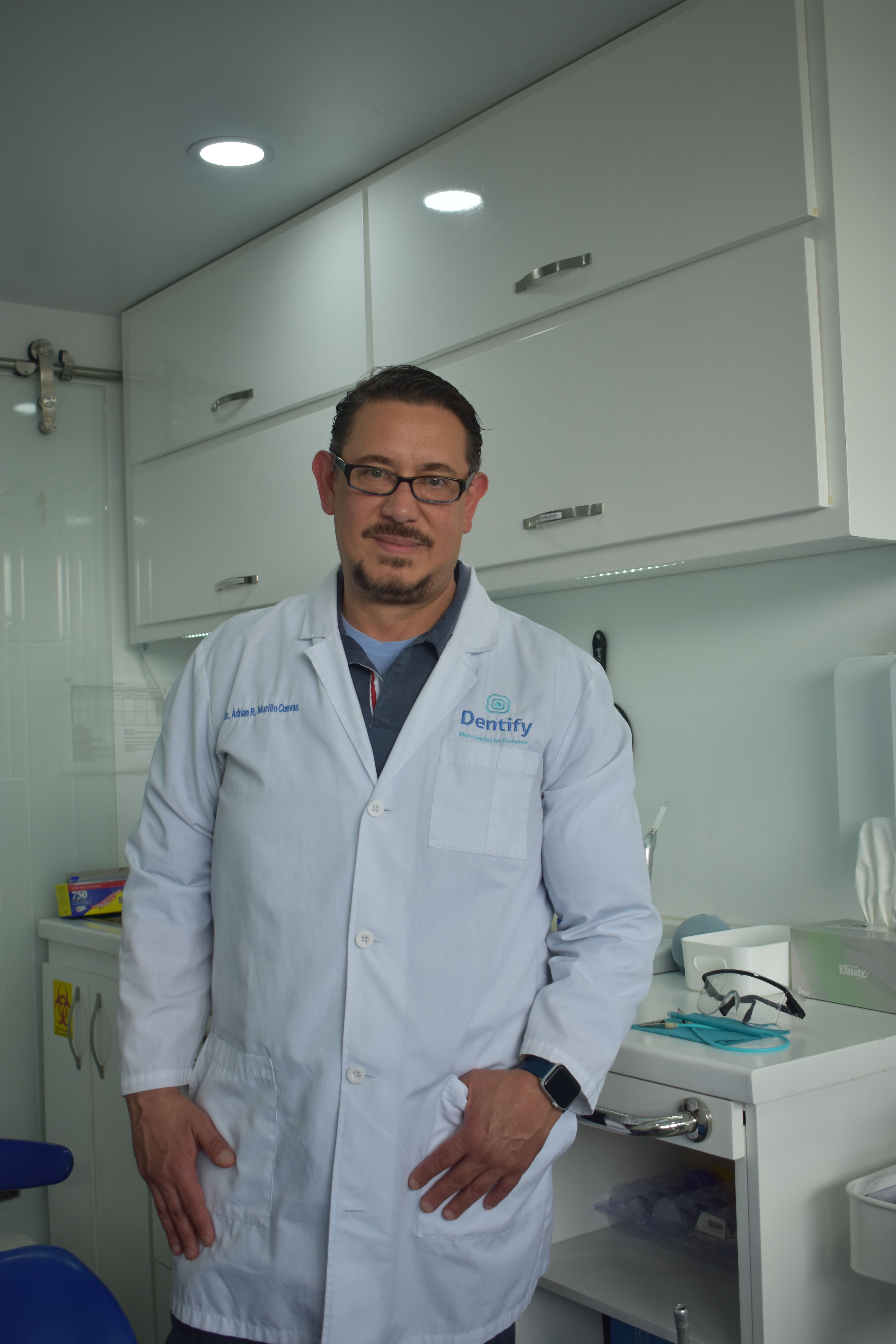 Dentist in a modern clinic posing confidently in a white coat, representing dental professionalism.