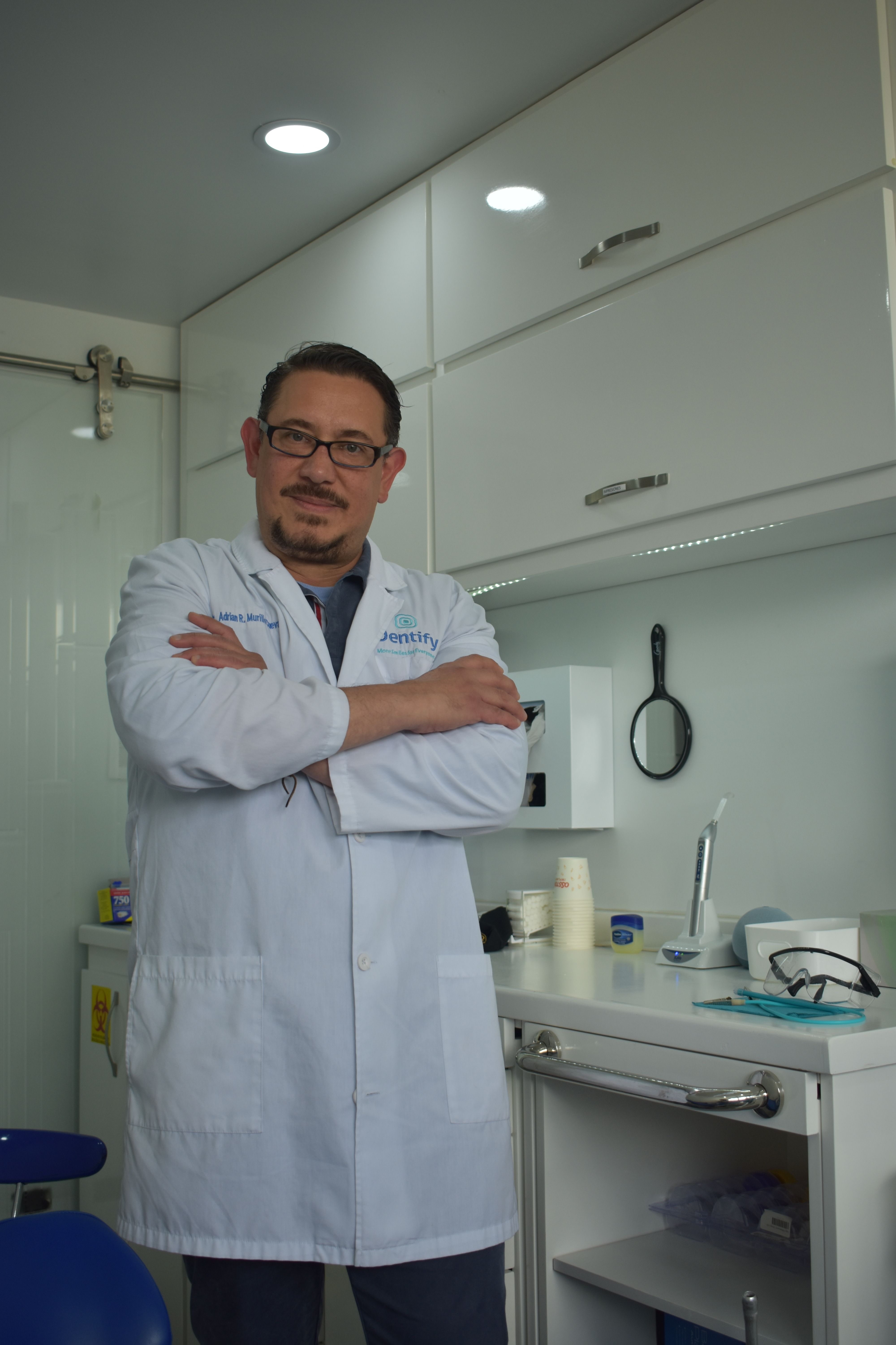 Confident dentist standing in a modern dental office with arms crossed, ready to assist patients.