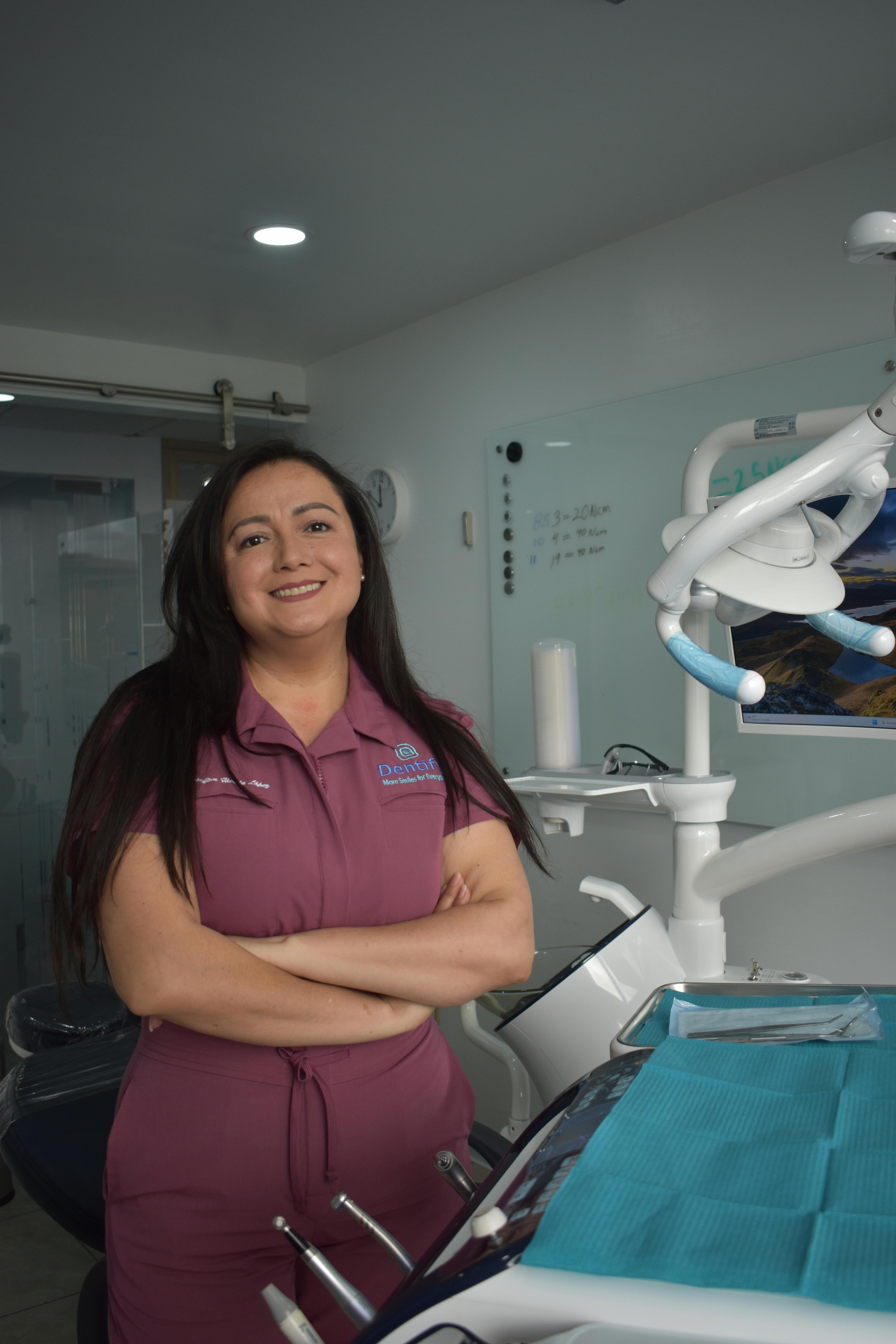 A smiling female dentist stands confidently in a modern dental clinic, ready to assist patients.