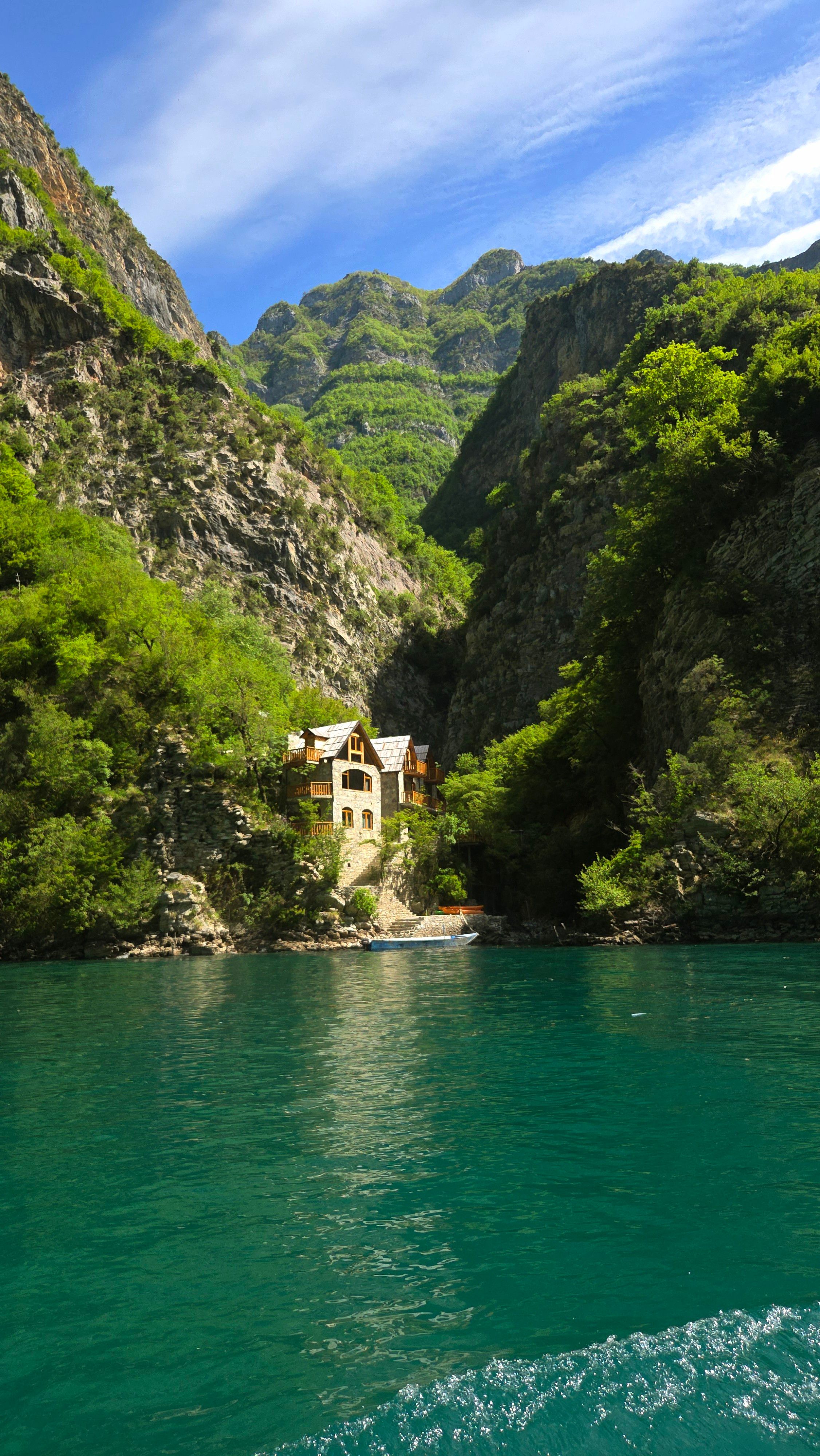 Charming house nestled between lush mountains by a turquoise river in Albania.