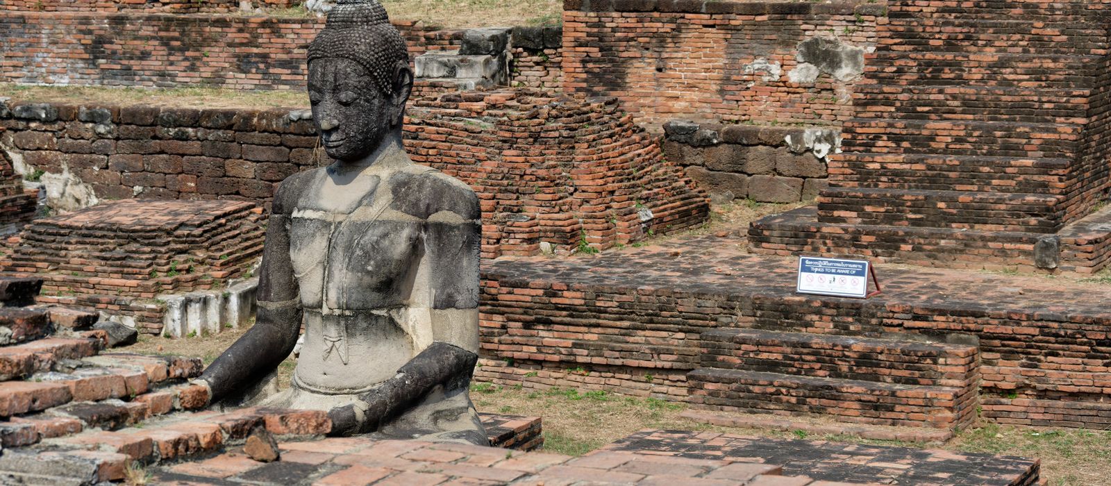 Ruins of Wat Mahathat with an ancient Buddha statue in Ayutthaya, Thailand.