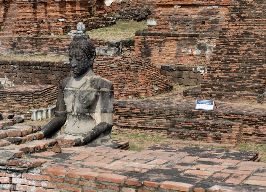 Ruins of Wat Mahathat with an ancient Buddha statue in Ayutthaya, Thailand.