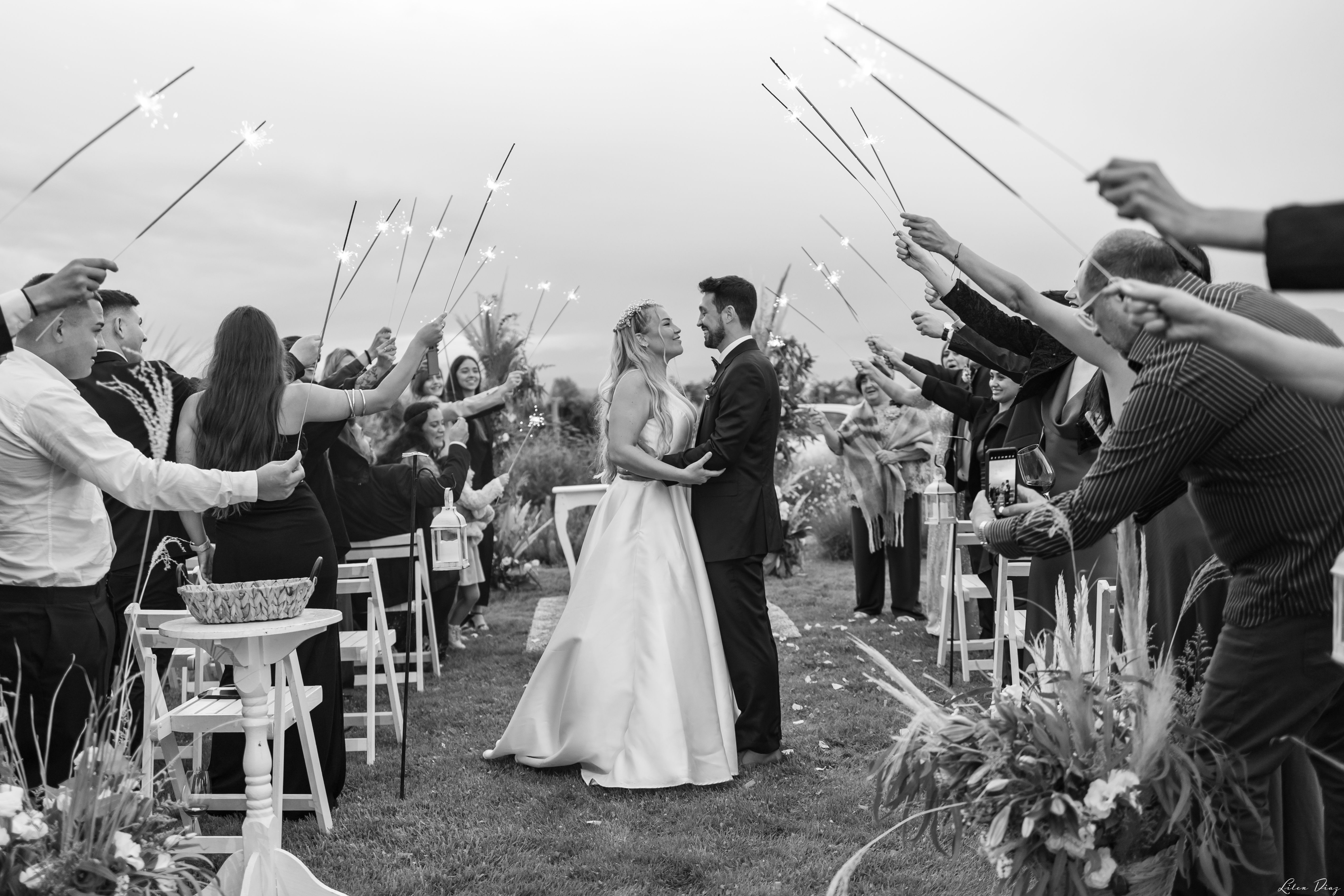 Bride and groom embrace under sparklers in a charming outdoor wedding ceremony.