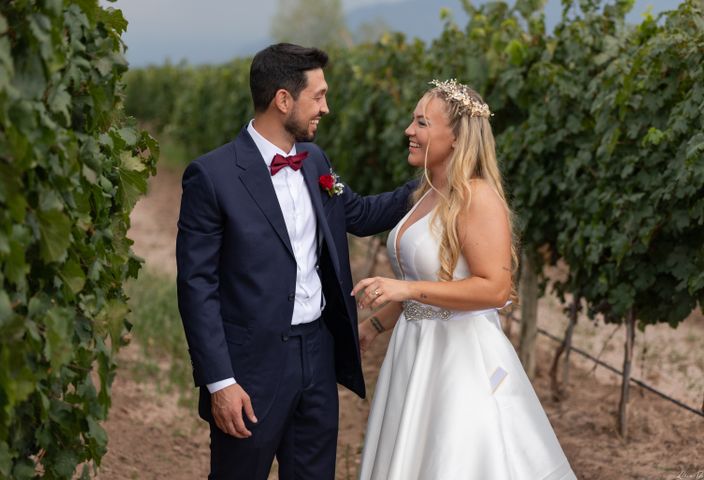 A couple enjoys a romantic vineyard wedding in Mendoza, dressed in elegant attire.