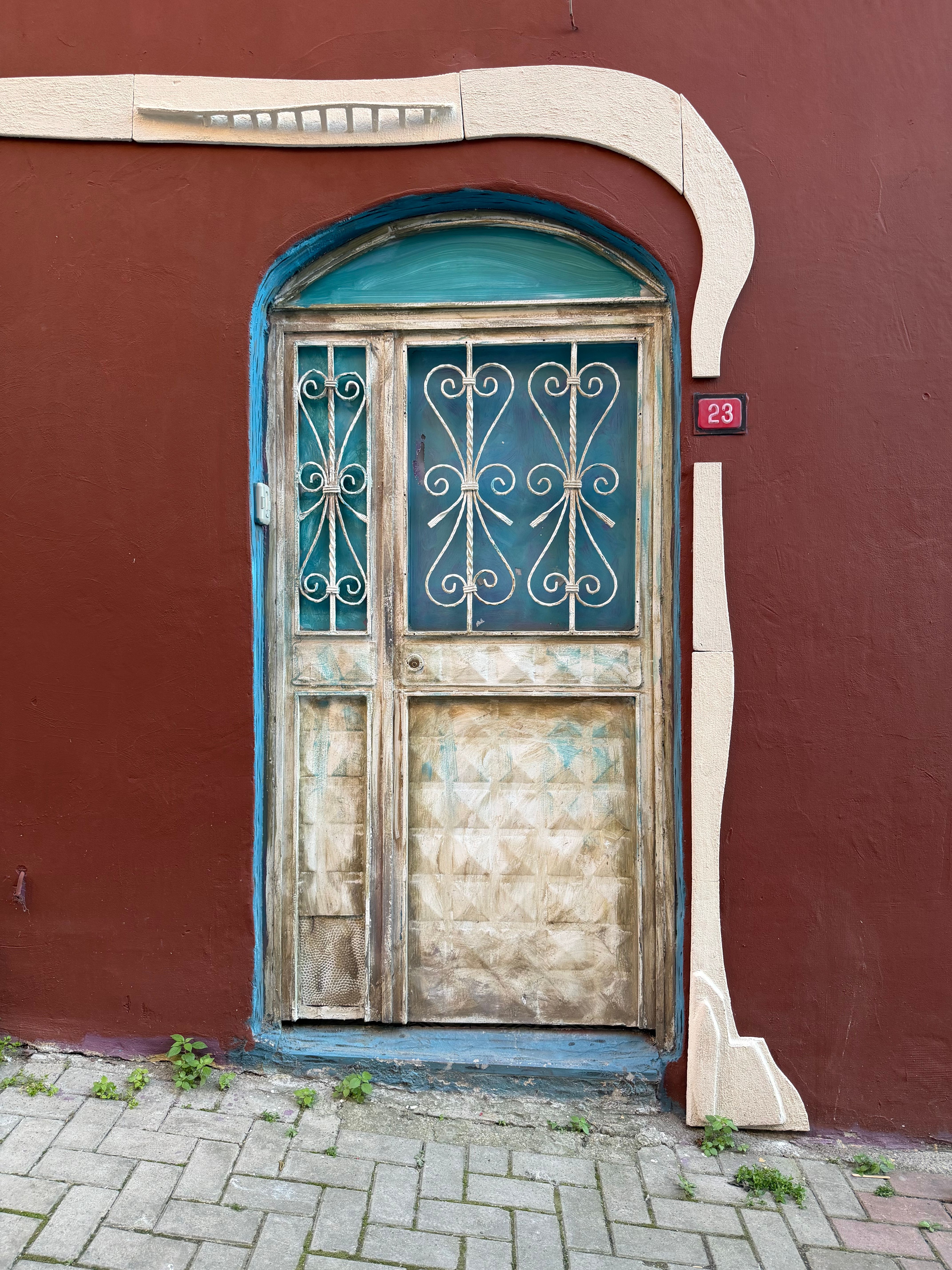 A vintage wooden door with a unique artistic frame on a red wall, detailed and textured.