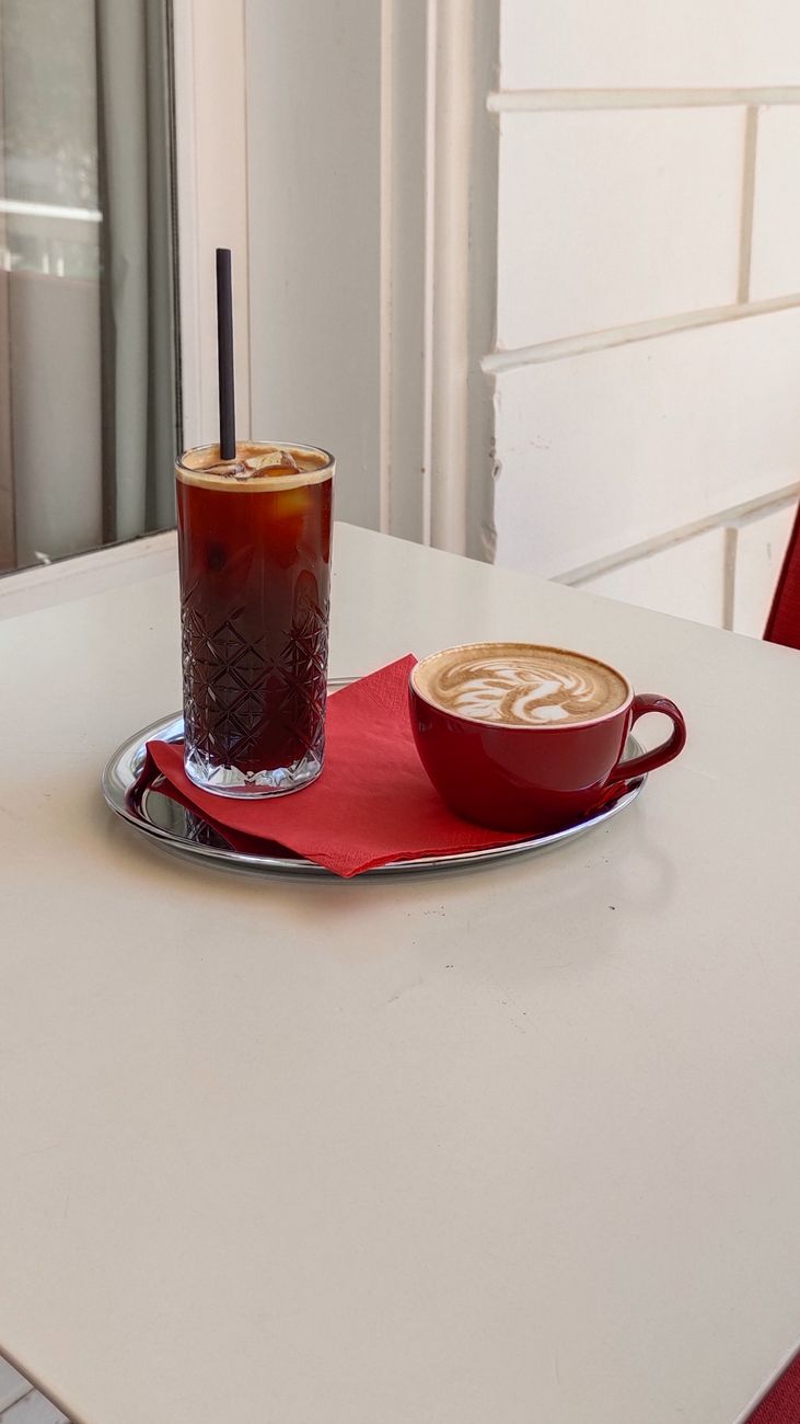 A stylish setup of iced coffee and a cappuccino on a cafe table, offering a cozy ambiance.