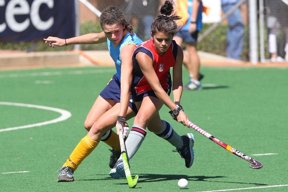 Women playing field hockey in coordinated sports uniforms on turf