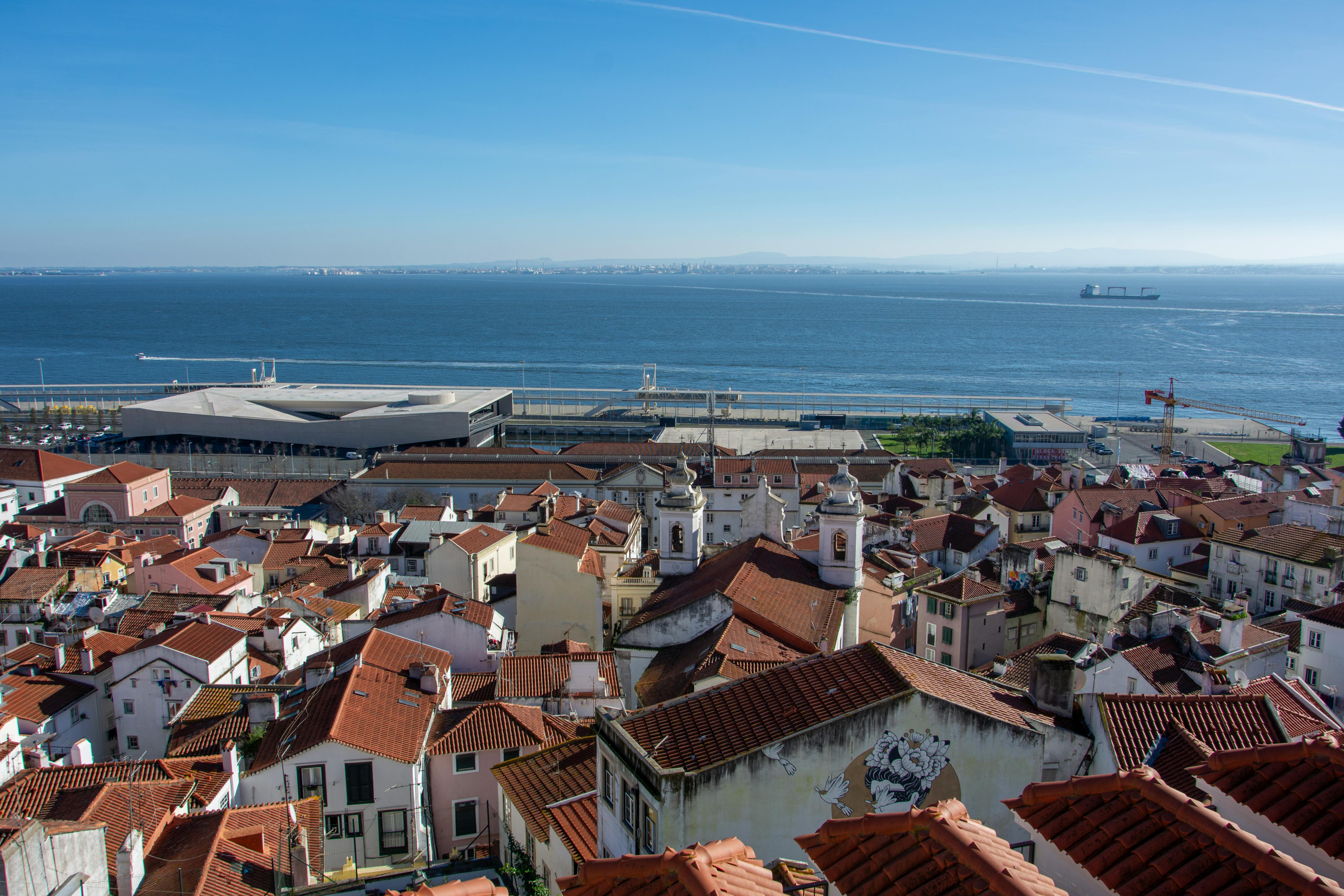 Lisbon rooftop co-working space with view of the Tagus River and a person working on laptop