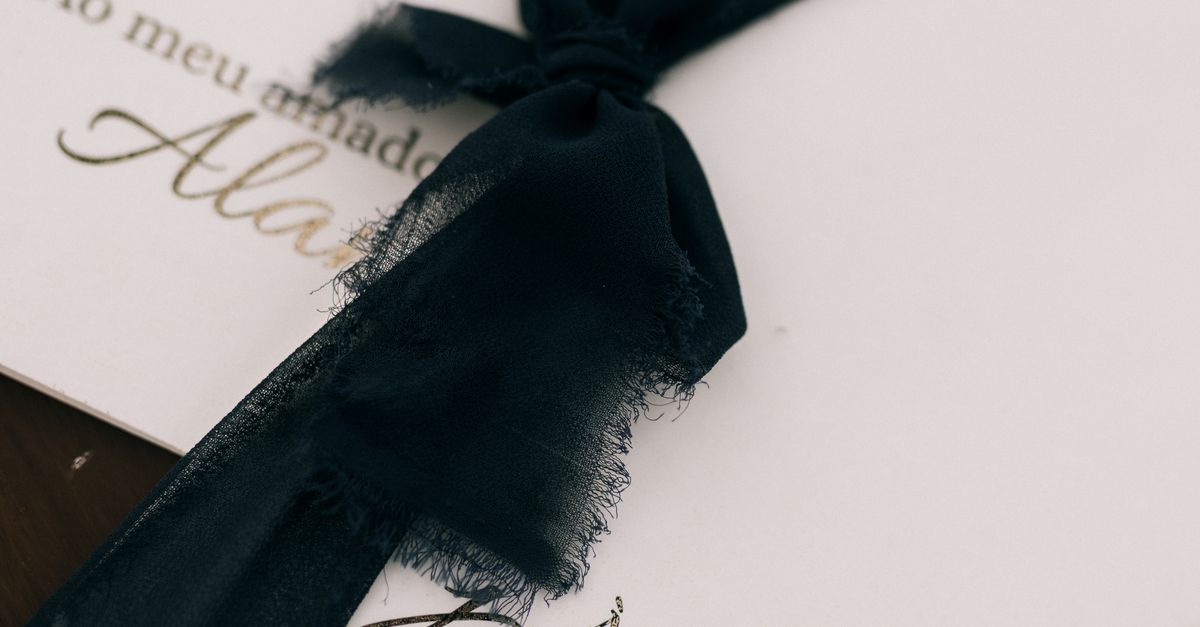 Elegant wedding invitations featuring dark ribbons and personalized text.