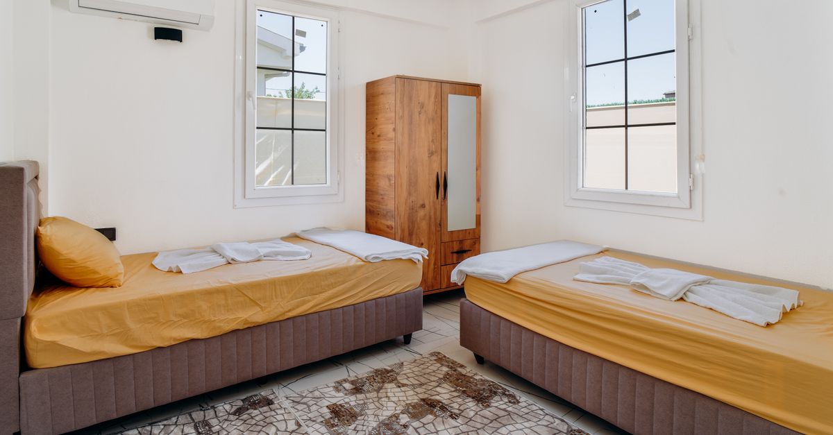 A minimalist bedroom featuring two neatly made twin beds with yellow sheets.