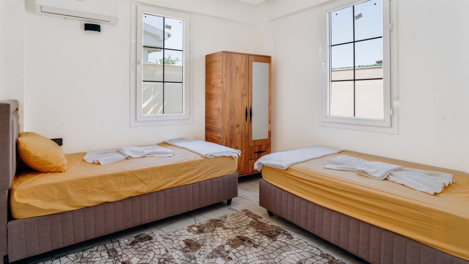 Two single beds with yellow covers in a bright room
