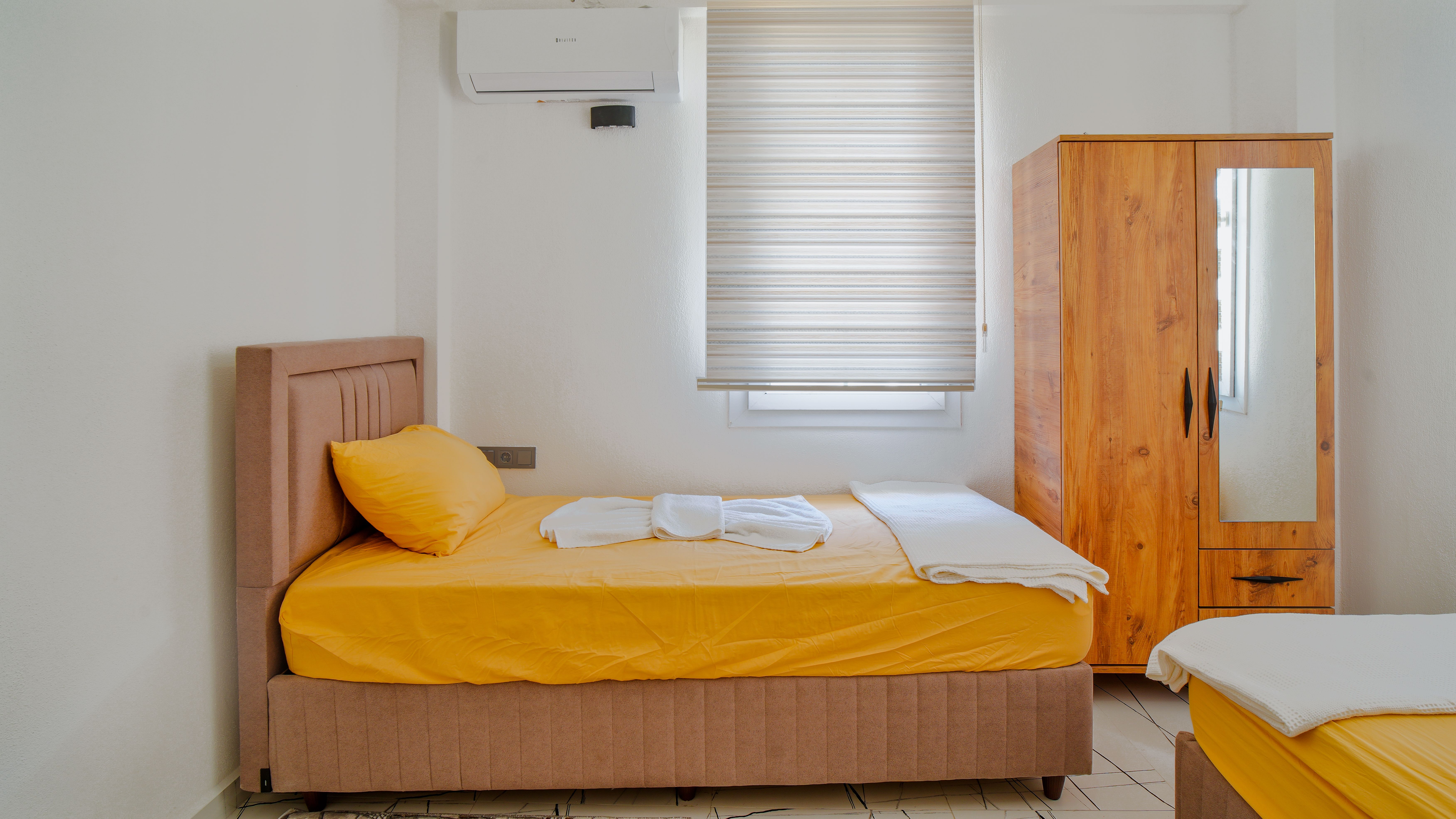 Compact single guest room with yellow bedding
