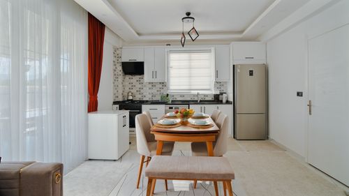 Free Contemporary kitchen and dining room with table set for four, featuring stylish decor and modern appliances. Stock Photo