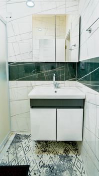 Bright white bathroom with marble tiles and a sleek vanity sink, emphasizing modern interior design.