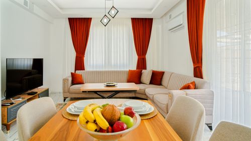 Free Bright modern living room with stylish sofa, vibrant curtains, and a fresh fruit bowl on the table. Stock Photo