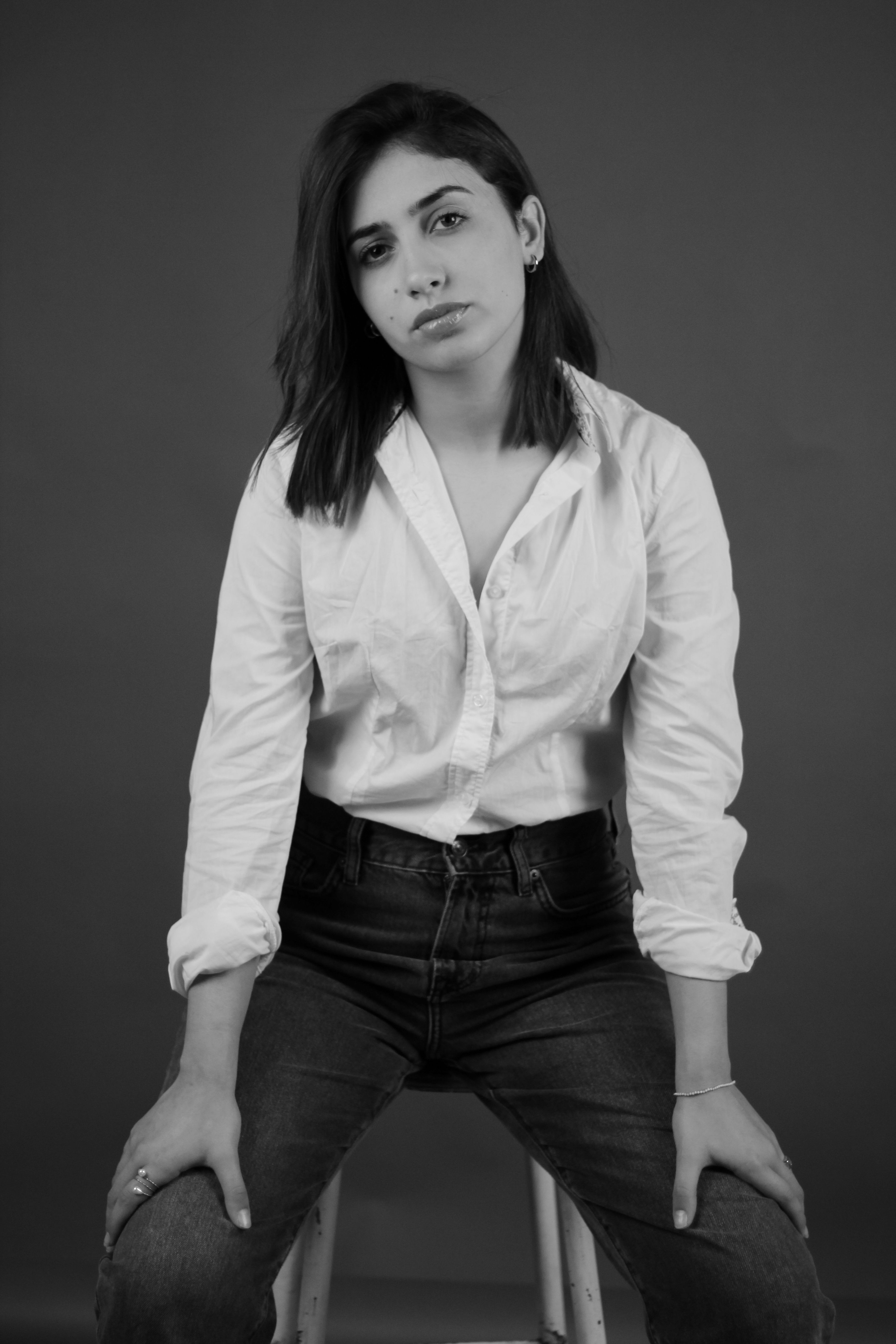 Artistic black and white portrait of a young woman wearing a white shirt and jeans.