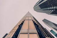 低角度视角下，圆滑的现代摩天大楼的玻璃立面反射着多云的天空