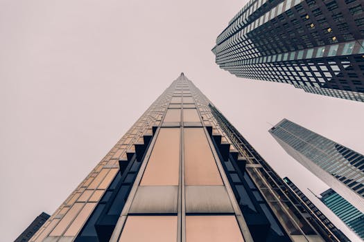 低角度视角下，圆滑的现代摩天大楼的玻璃立面反射着多云的天空