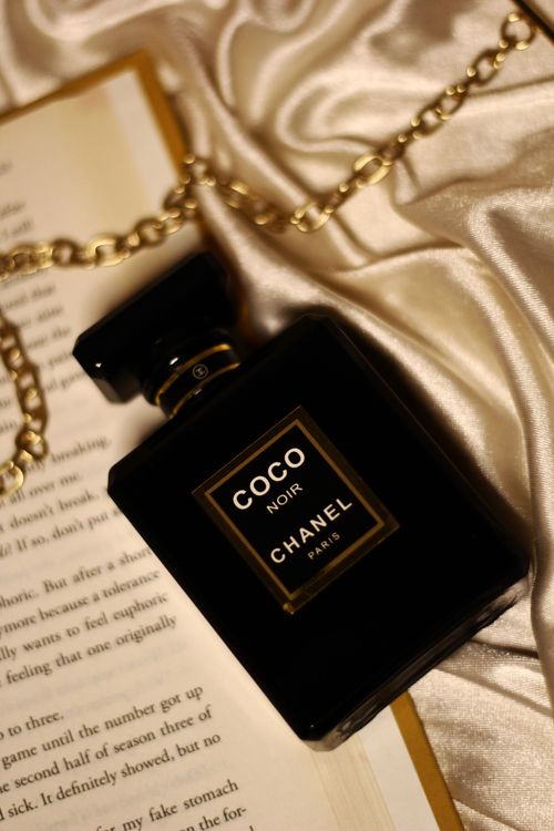 Free Chanel Coco Noir perfume bottle on silk with book, elegant and luxurious setting. Stock Photo