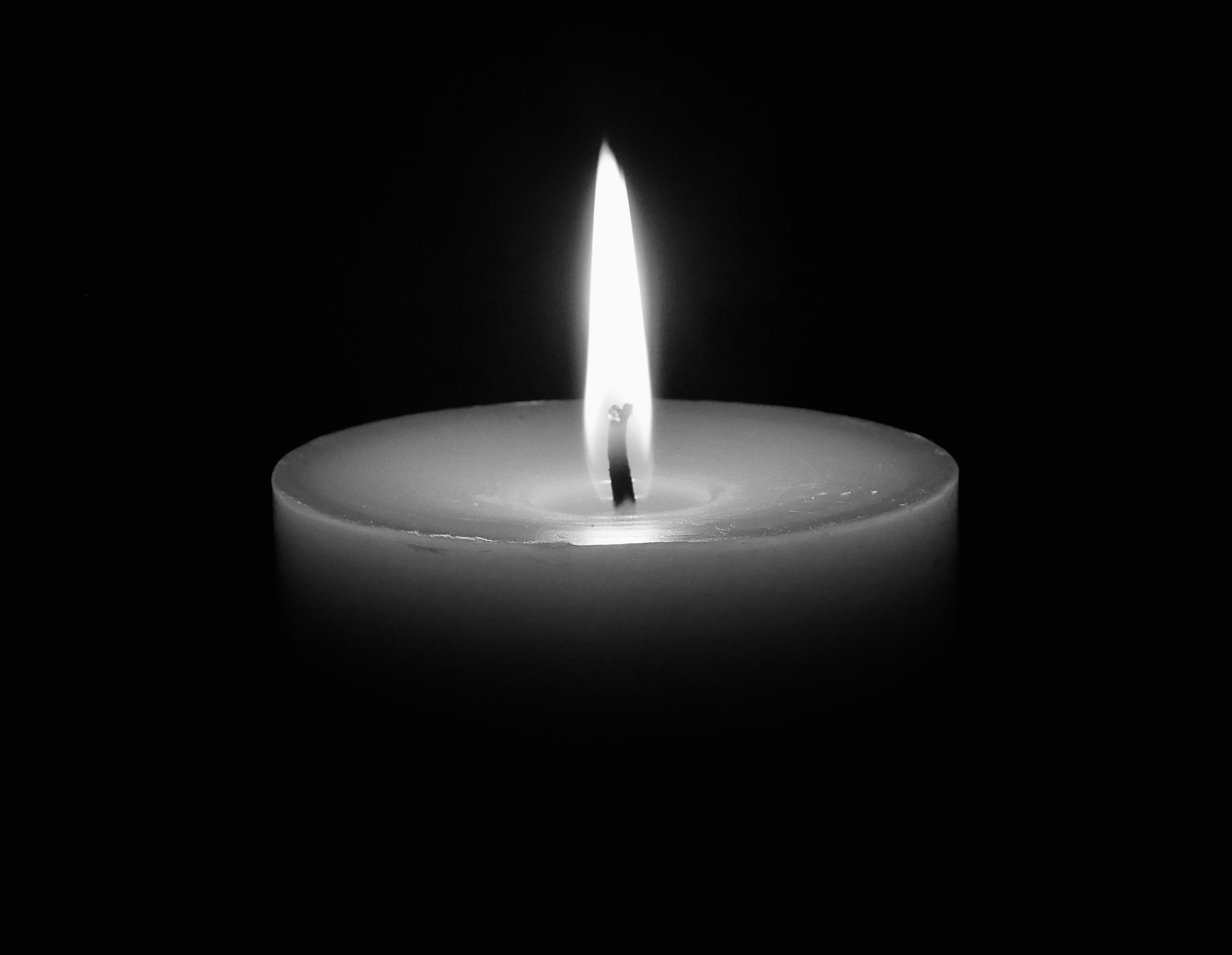 A calming image of a single candle flame glowing in the dark, offering serenity.