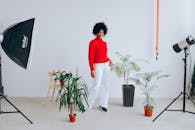 一位穿着红色毛衣的自信女人在摄影工作室里与室内植物合影