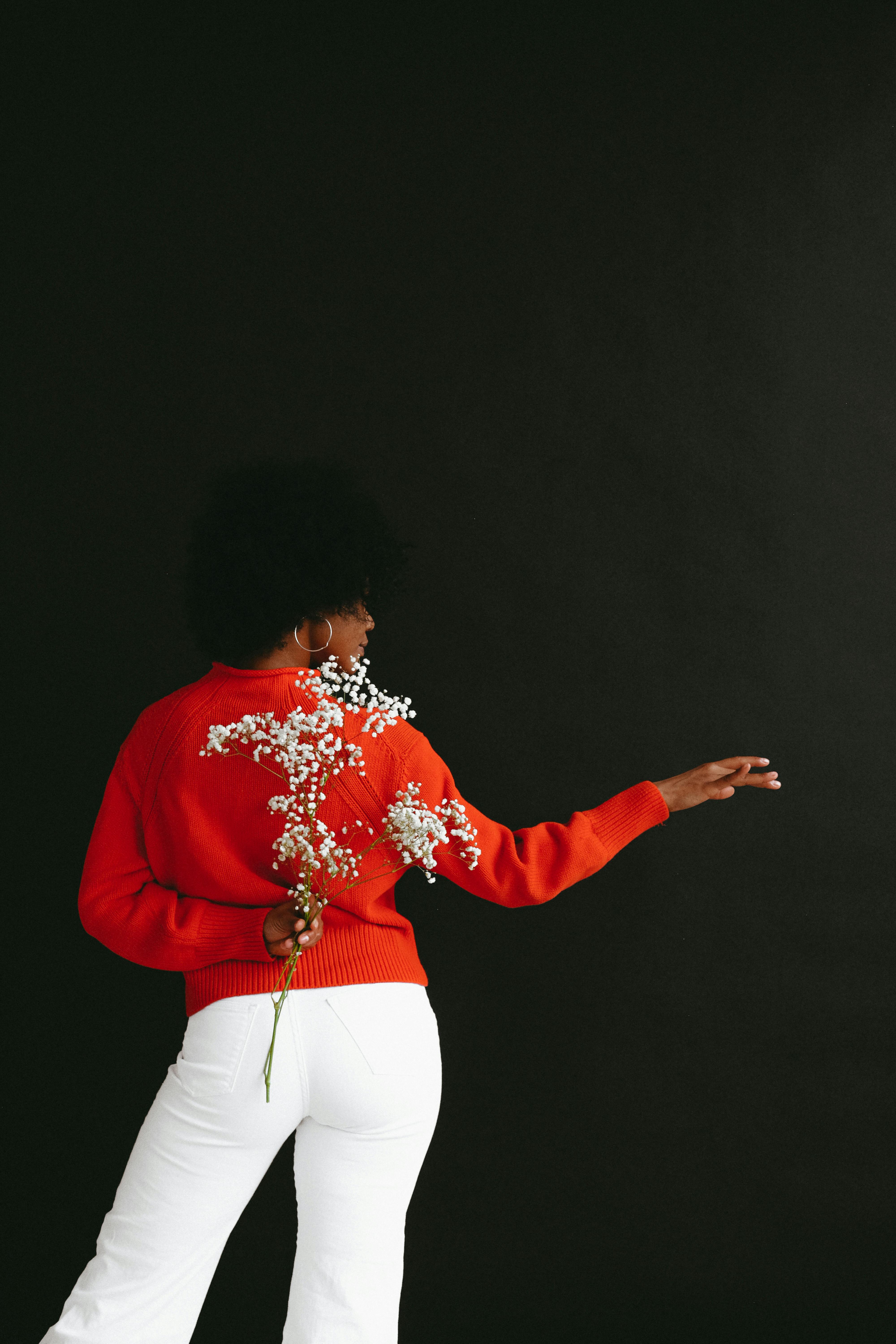 dancing black woman hiding flower behind back in studio