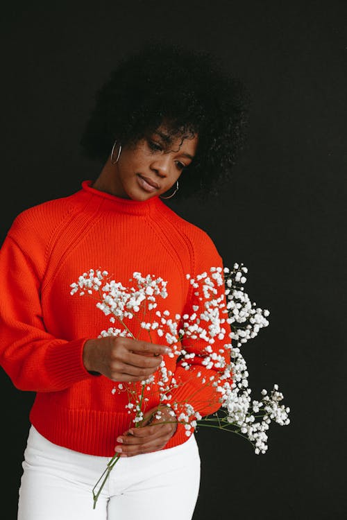 Woman in Red Sweater Holding White Flowers