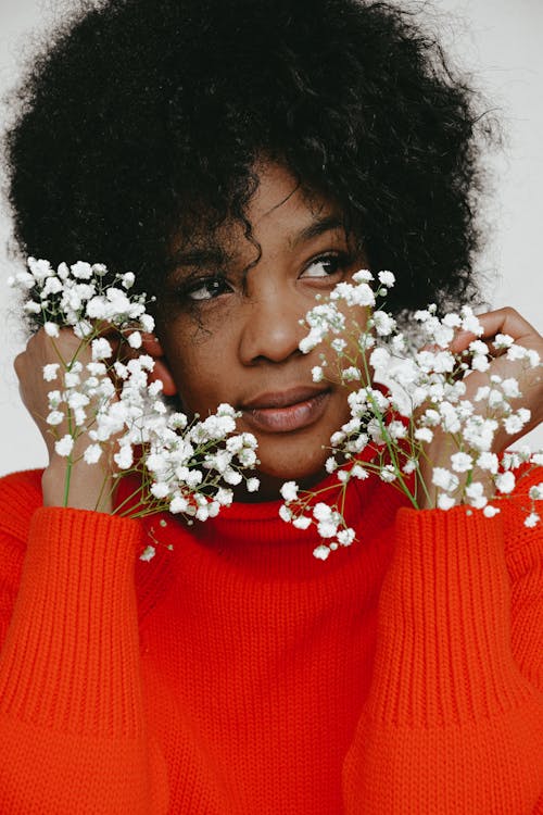 Woman in Red Turtleneck Sweater With White Flowers on Her Ear