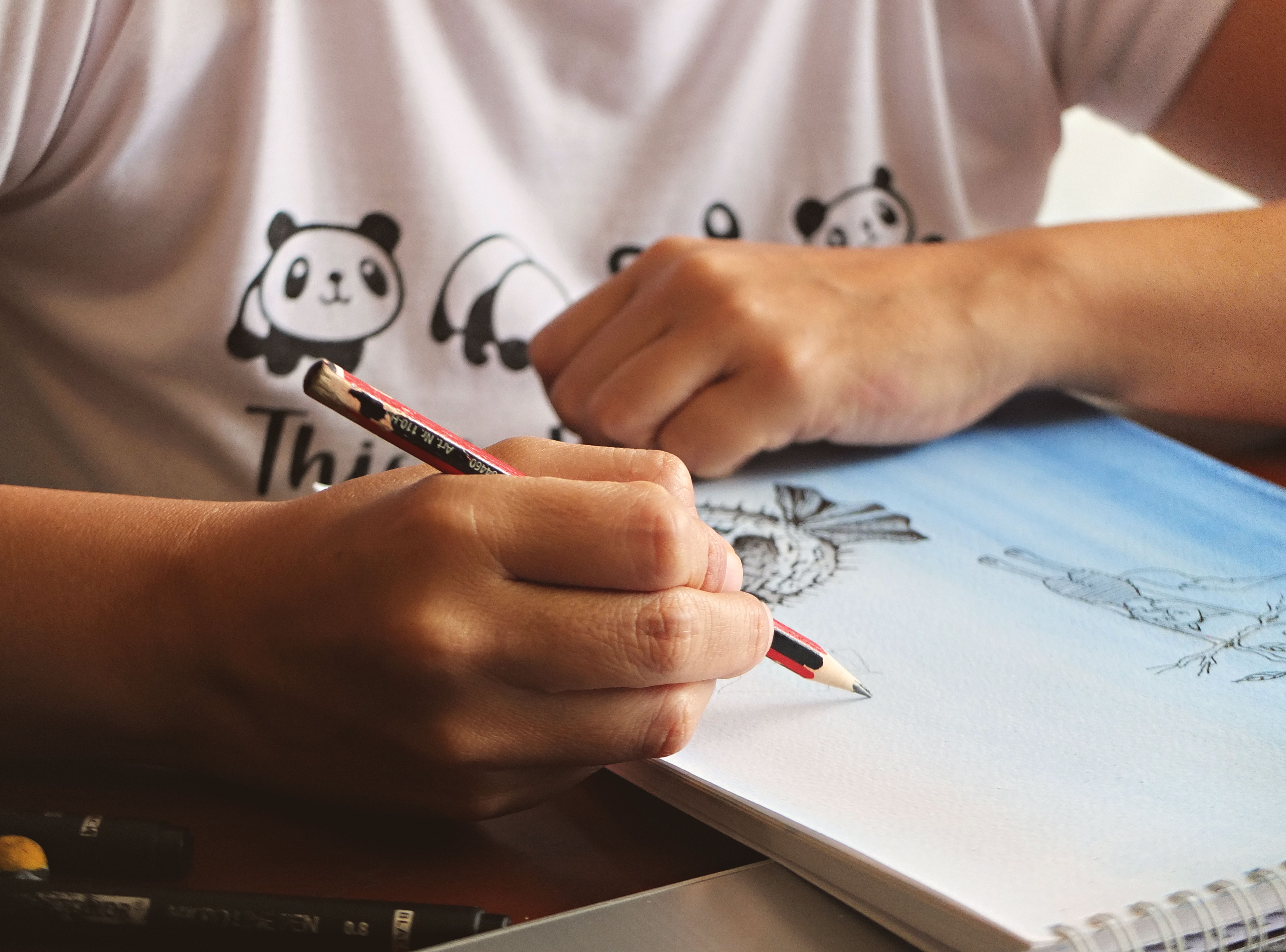Close-up of an adult sketching a drawing with a pencil in a notebook. Creative and artistic activity.
