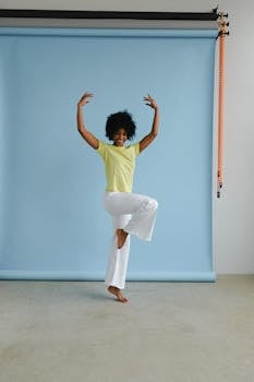 一位非裔美国女性，留着非洲发型，在蓝色背景的工作室里快乐地摆着姿势