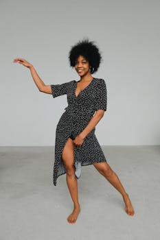 一位开朗的黑人女性穿着圆点连衣裙在室内跳舞，展现了非洲发型与风格