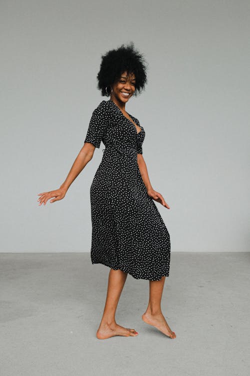 Woman in Black and White Polka Dots Dress Standing on Concrete Floor