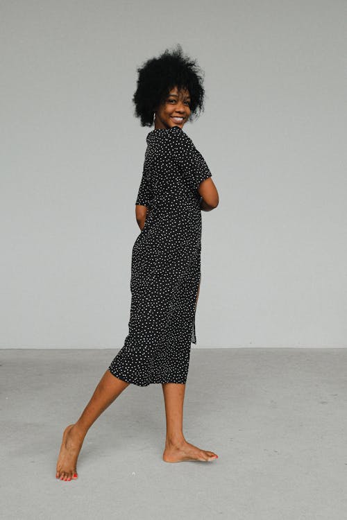 Woman in Black and White Polka Dots Dress Standing on Floor